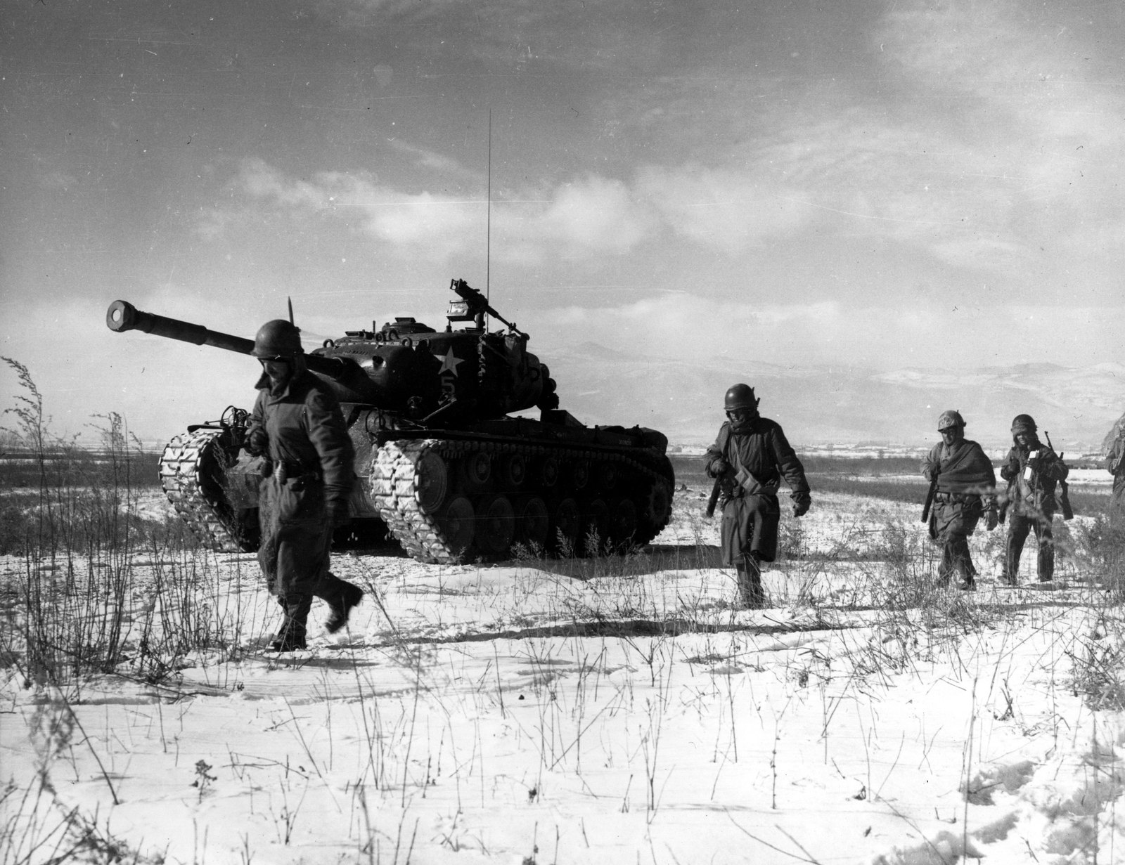 Marines of the 1st Marine Division walk through snow beside an M26 Pershing tank during the breakout from the Chosin Reservoir, December 1950