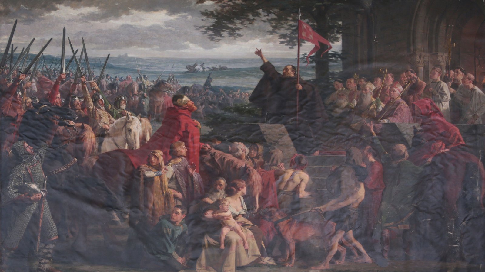 Painting of a monk in a dark habit raising his arm and preaching from steps under a red banner, a crowd of mounted knights with lances, women and children gathered around him.