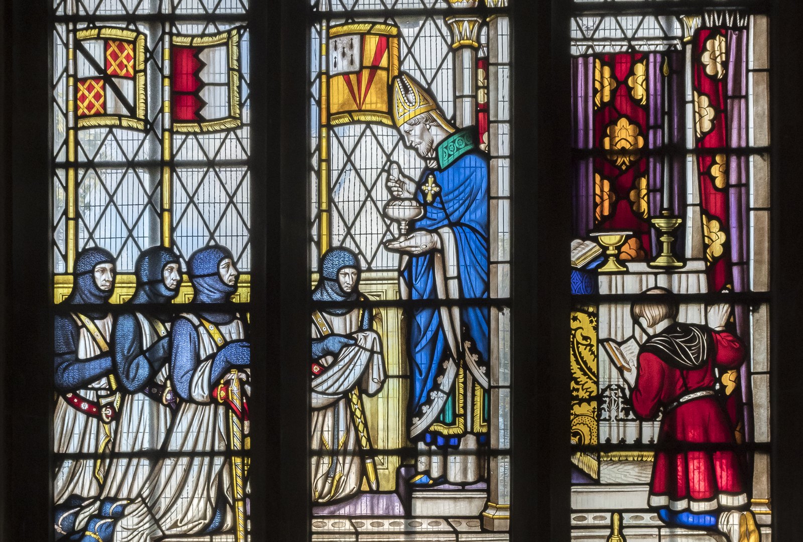 Stained glass window showing Simon de Montfort and his knights in hooded mail kneeling to receive communion from a bishop before the battle, with heraldic banners above them.