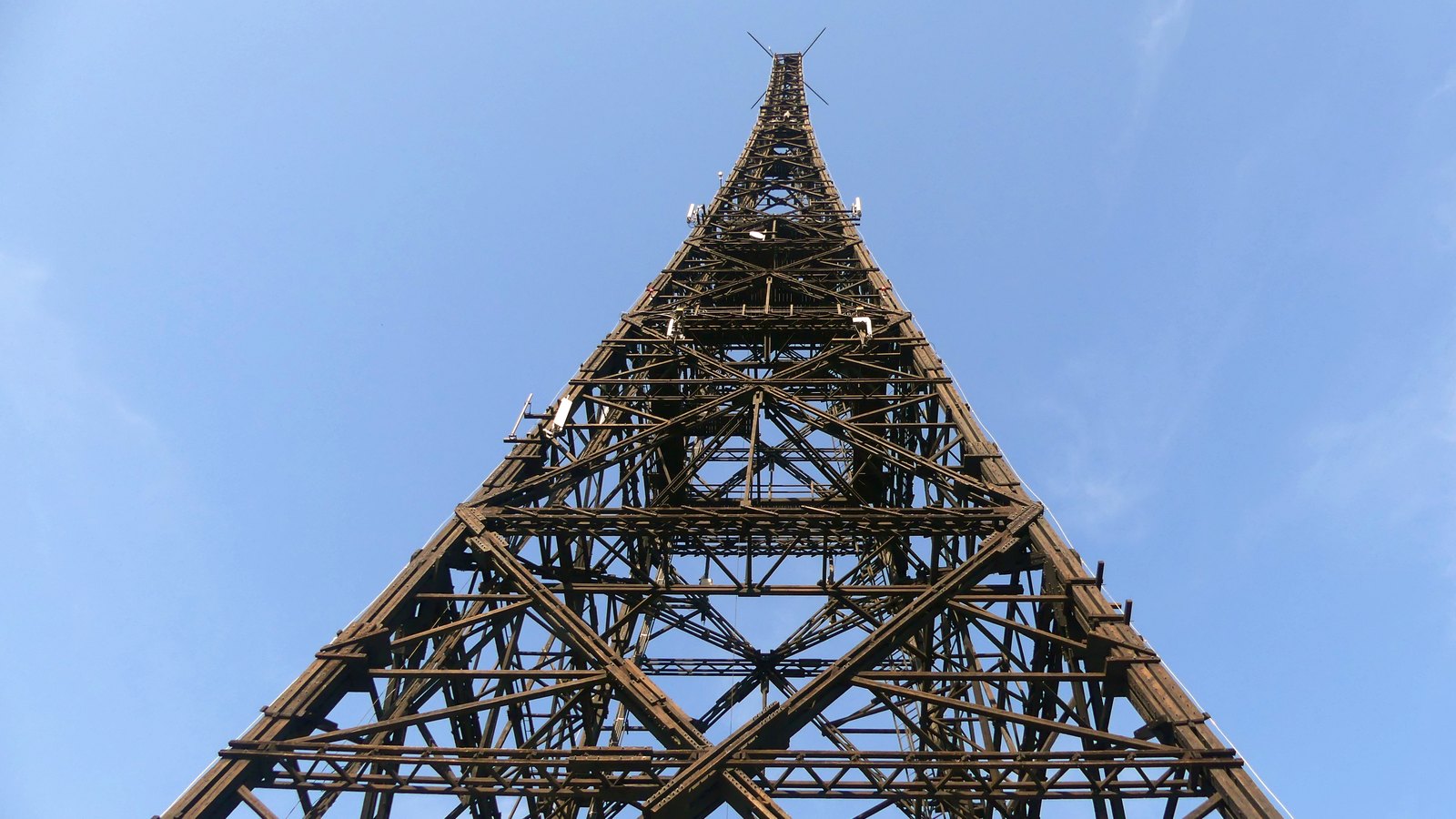 Looking straight up the wooden lattice transmitter tower of the Gliwice radio station against a blue sky.