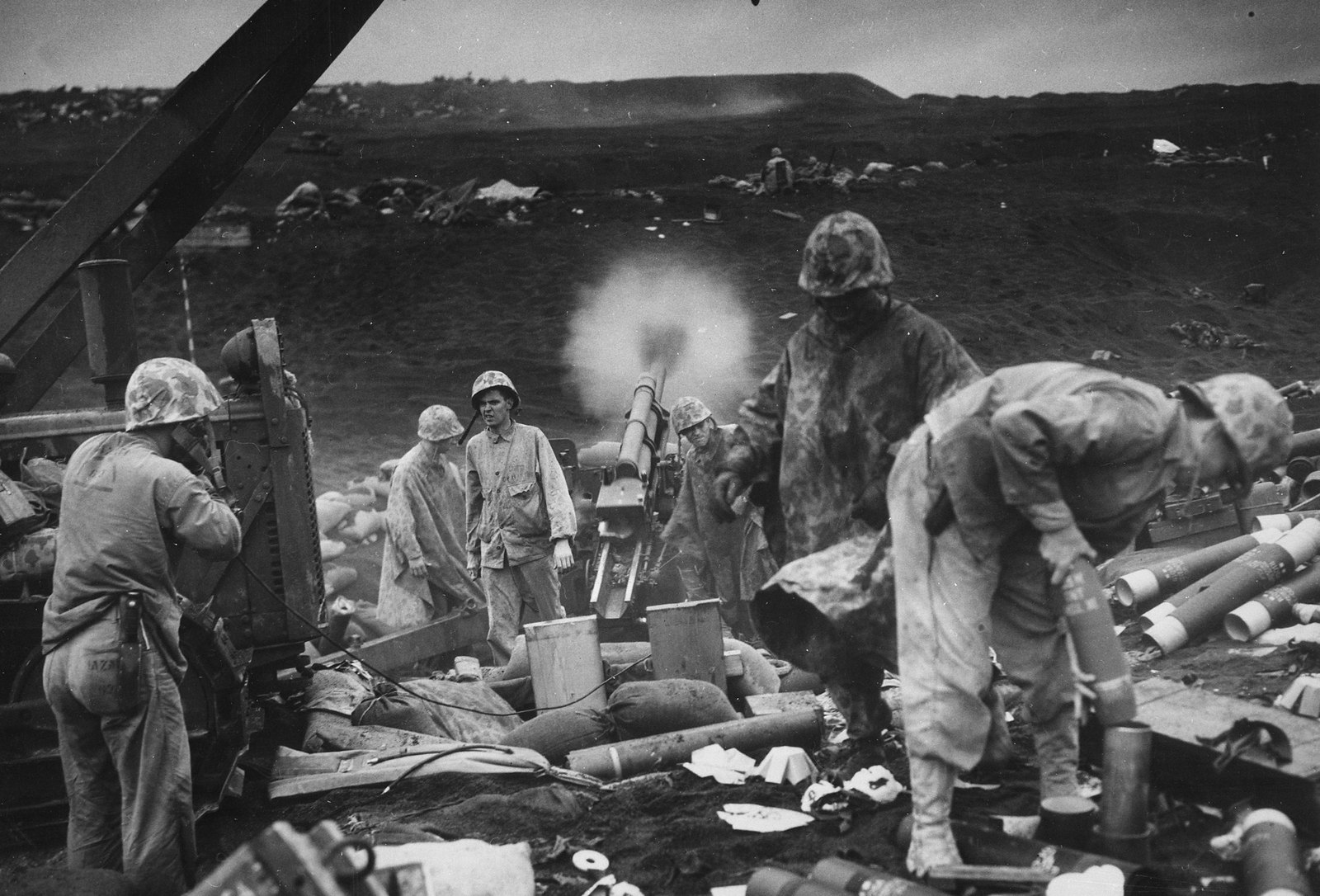 US Marines of the 4th Division fire an artillery piece among spent shell casings on the black volcanic sand of Iwo Jima, 1945