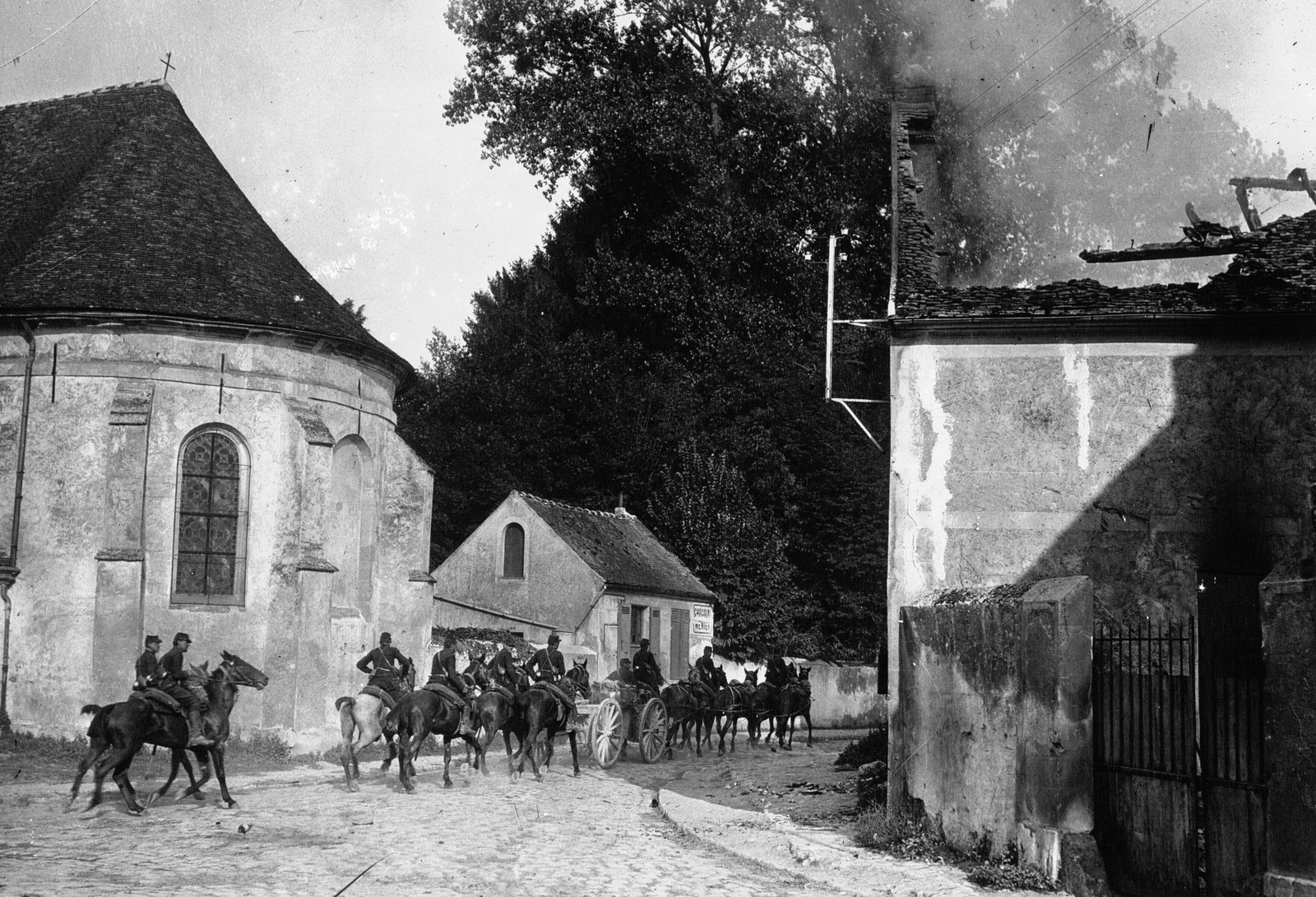 Francuska artyleria konna przejeżdża przez wieś Chauconin pod Meaux obok kościoła i płonącego domu na początku września 1914 roku, u progu bitwy nad Marną