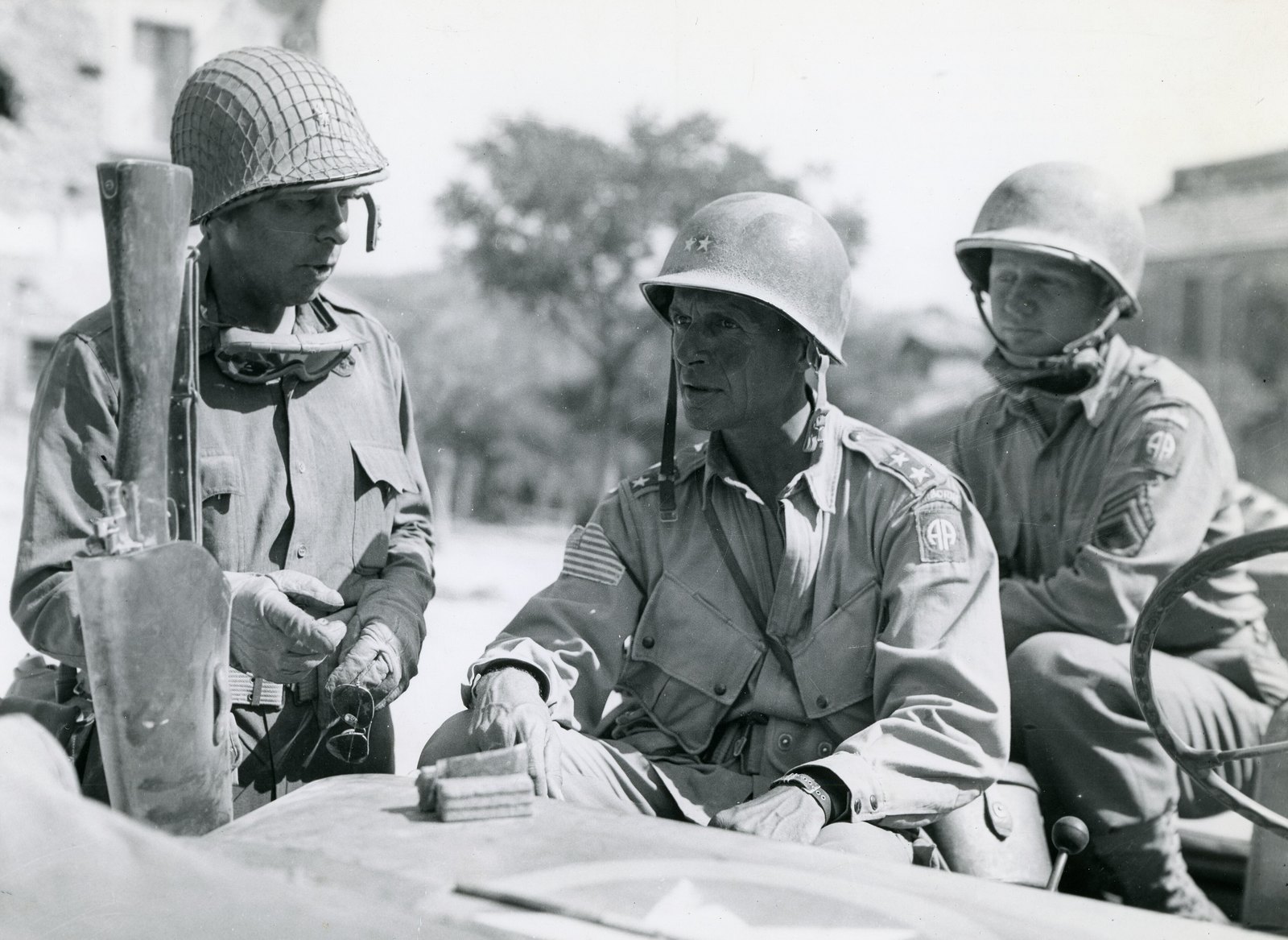Photograph of Major General Matthew Ridgway in a steel helmet seated in a jeep with 82nd Airborne soldiers, Italy 1943