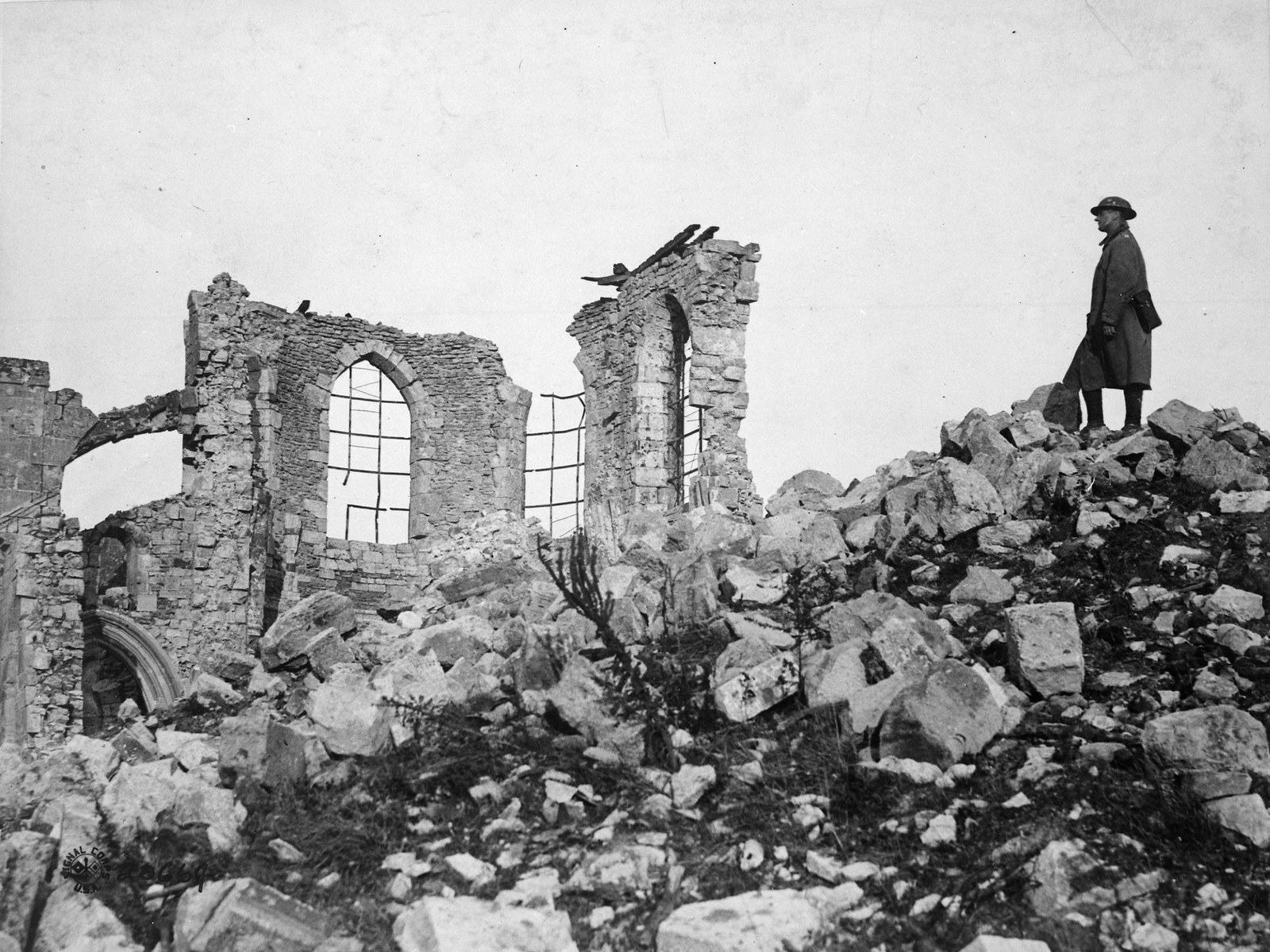 Amerykański żołnierz w płaszczu stoi na gruzach zrujnowanego kościoła na zdobytym wzgórzu Montfaucon, 1918