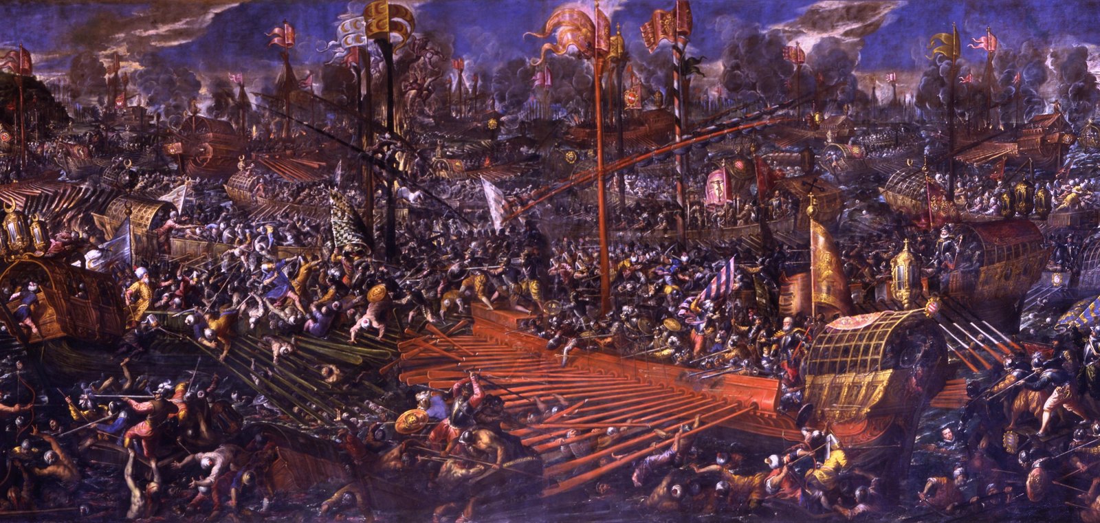 Crowded Venetian painting of the Battle of Lepanto: galleys with long red oars and gilded stern lanterns locked together, soldiers in armor and turbans fighting hand to hand across the decks and in the water, banners and smoke against a dark blue sky.