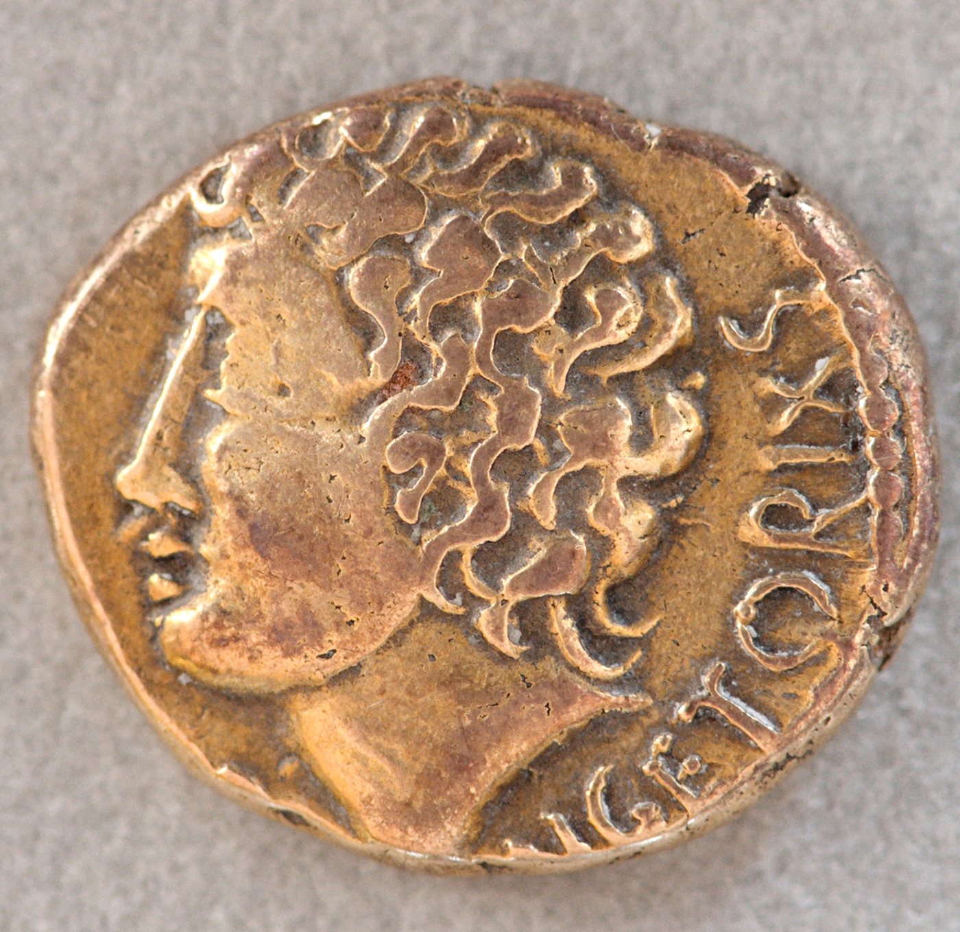 Ancient gold coin with a young male head in profile and a Latin legend