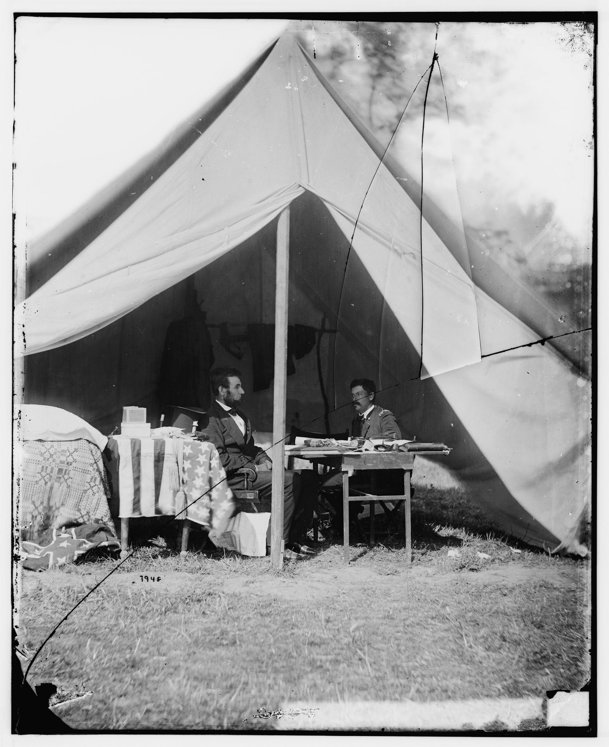 Abraham Lincoln seated facing George McClellan inside an army tent
