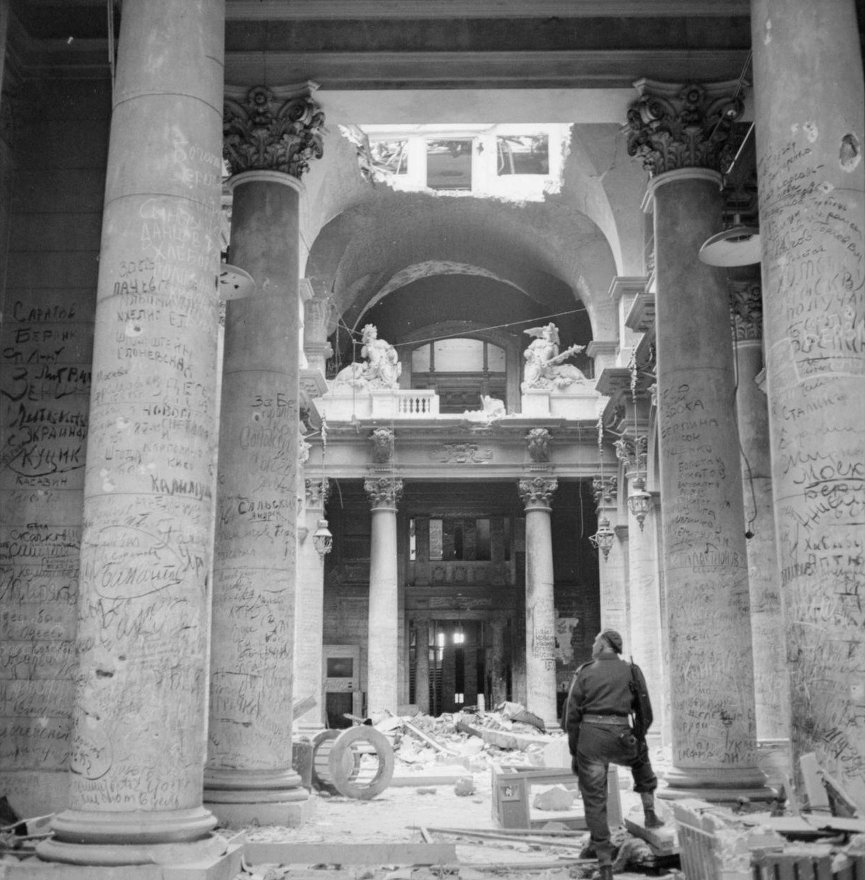 A soldier looks at graffiti-covered pillars inside the ruined Reichstag