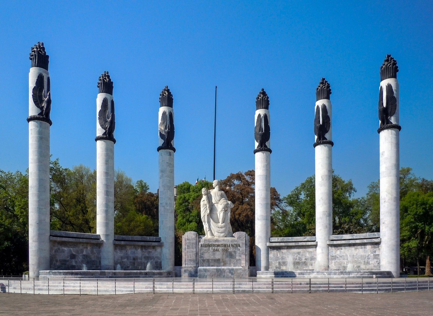 White marble monument with six tall columns around a central sculpture