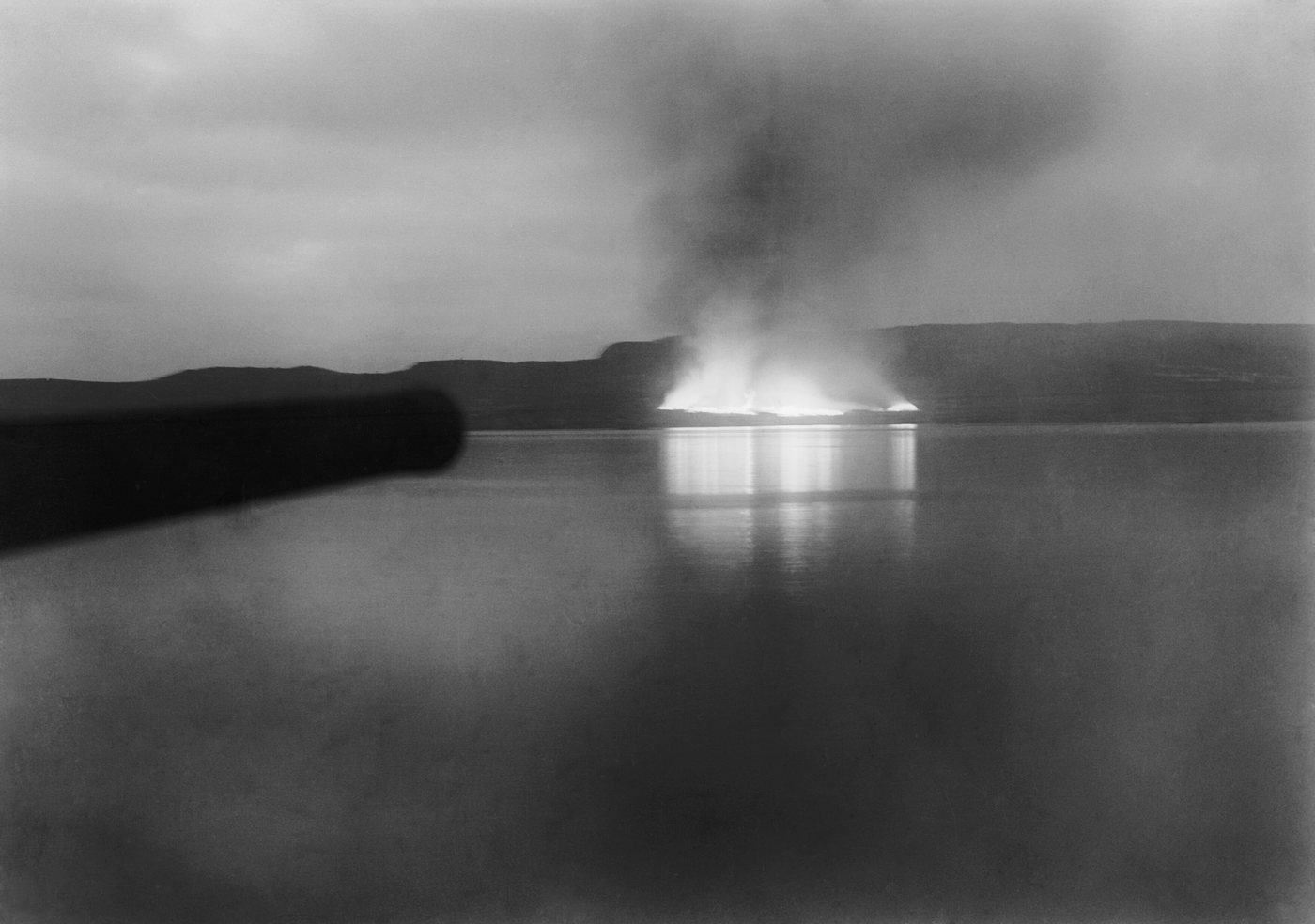 Night photograph of fires burning on a distant beach across dark water
