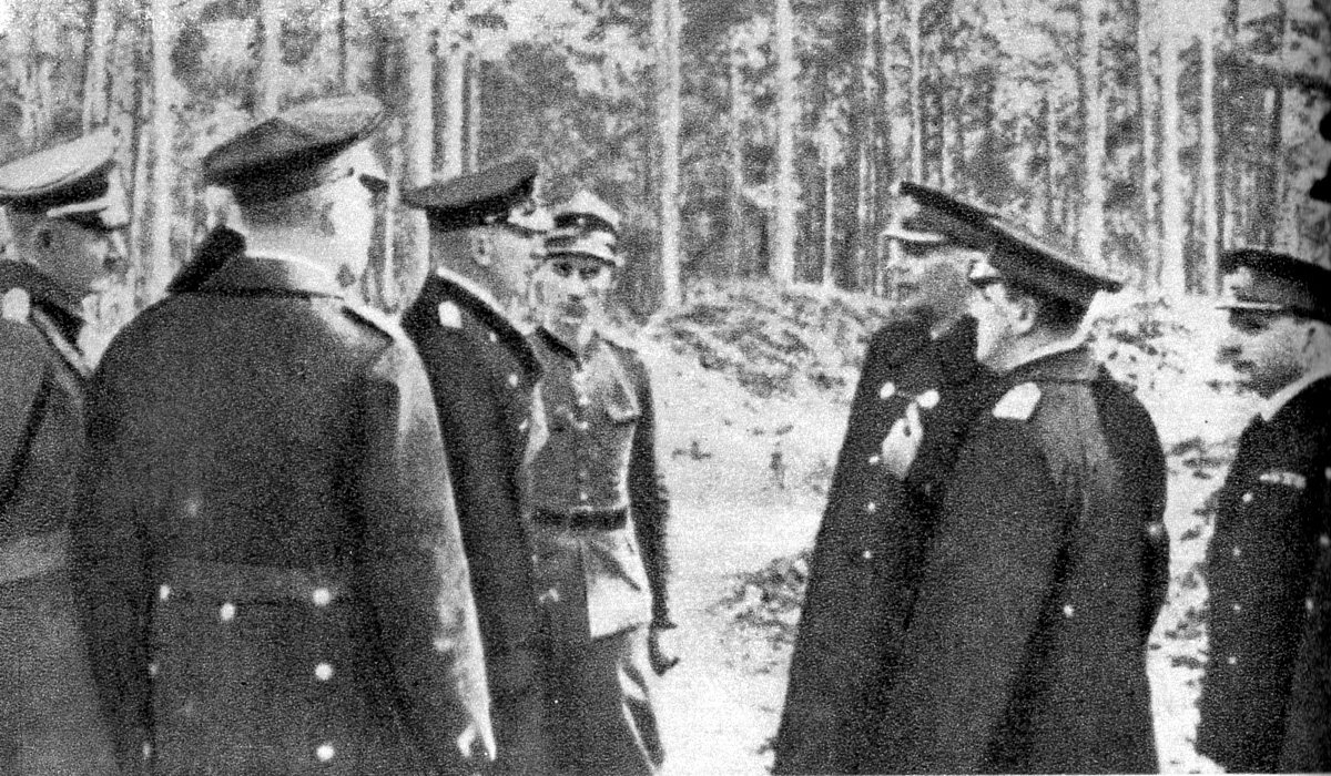 Photograph of Polish and German naval officers in greatcoats meeting among pine trees