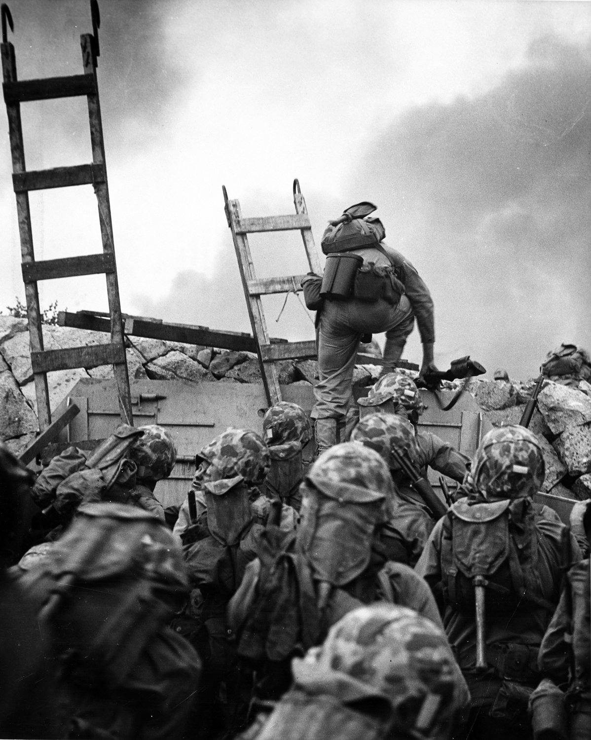 Photograph of a Marine climbing a ladder over a concrete seawall