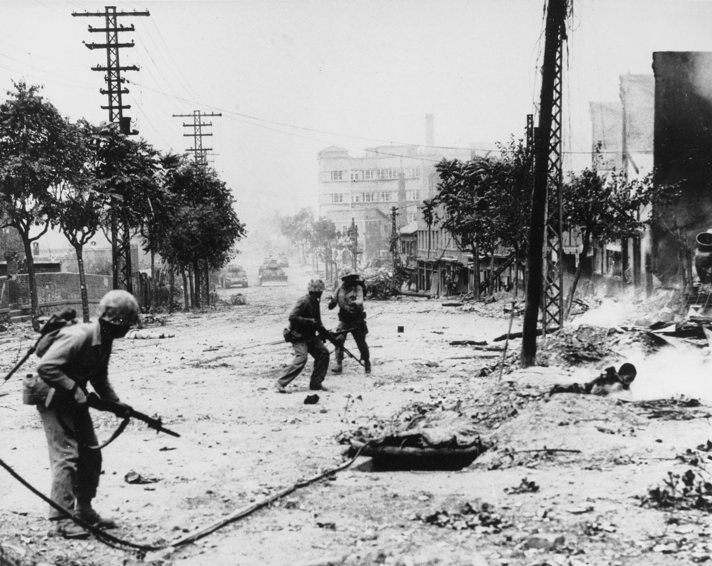 Photograph of Marines taking cover in a ruined street in Seoul