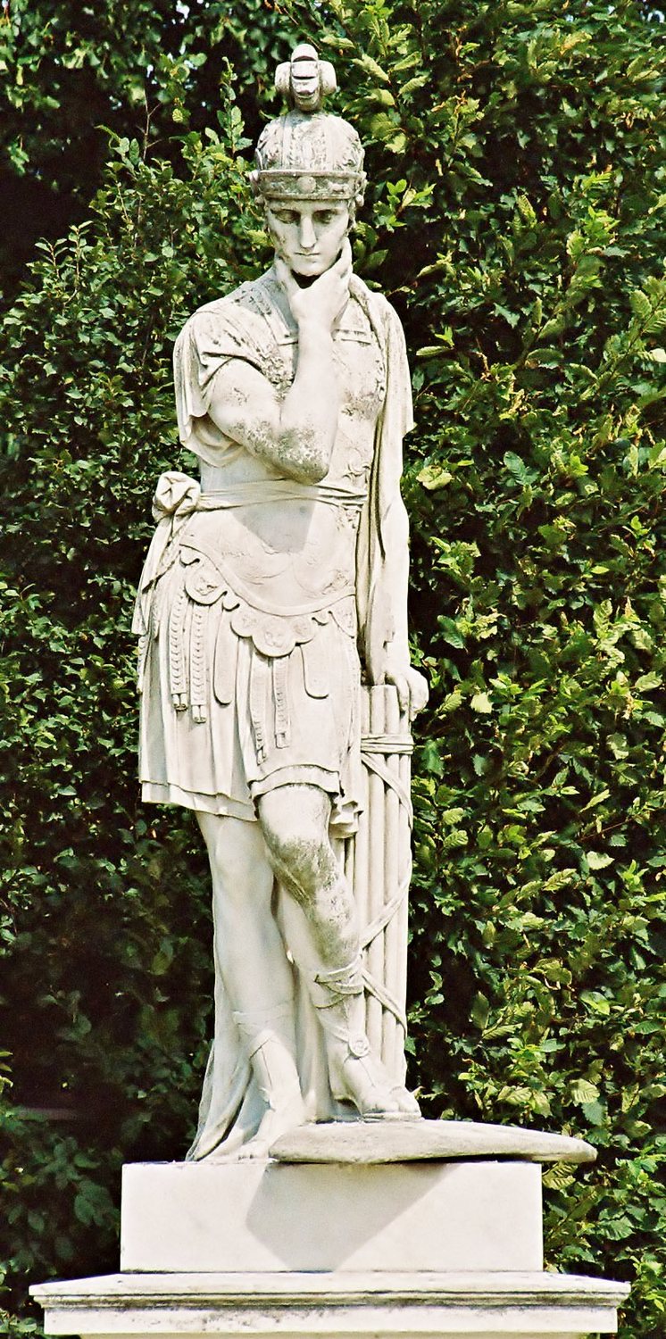 Marble statue of a Roman statesman in a toga standing on a pedestal in a garden