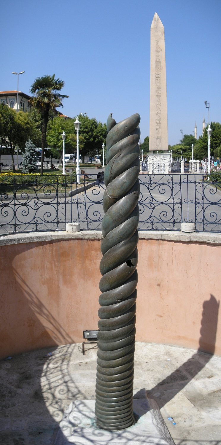 Twisted bronze column of intertwined snakes standing in a sunken enclosure