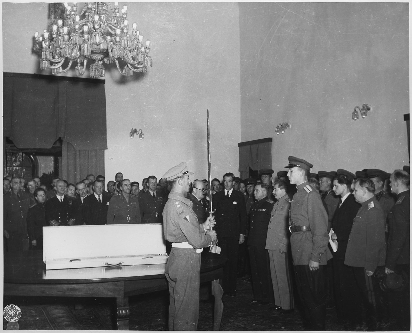 A British officer holds up a ceremonial sword before Stalin and Soviet officers in a hall
