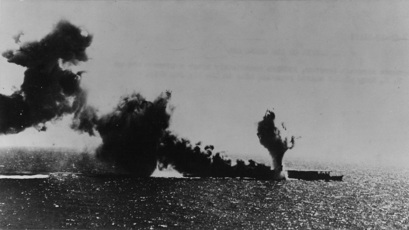 Aerial photograph of a Japanese carrier pouring black smoke after a torpedo hit