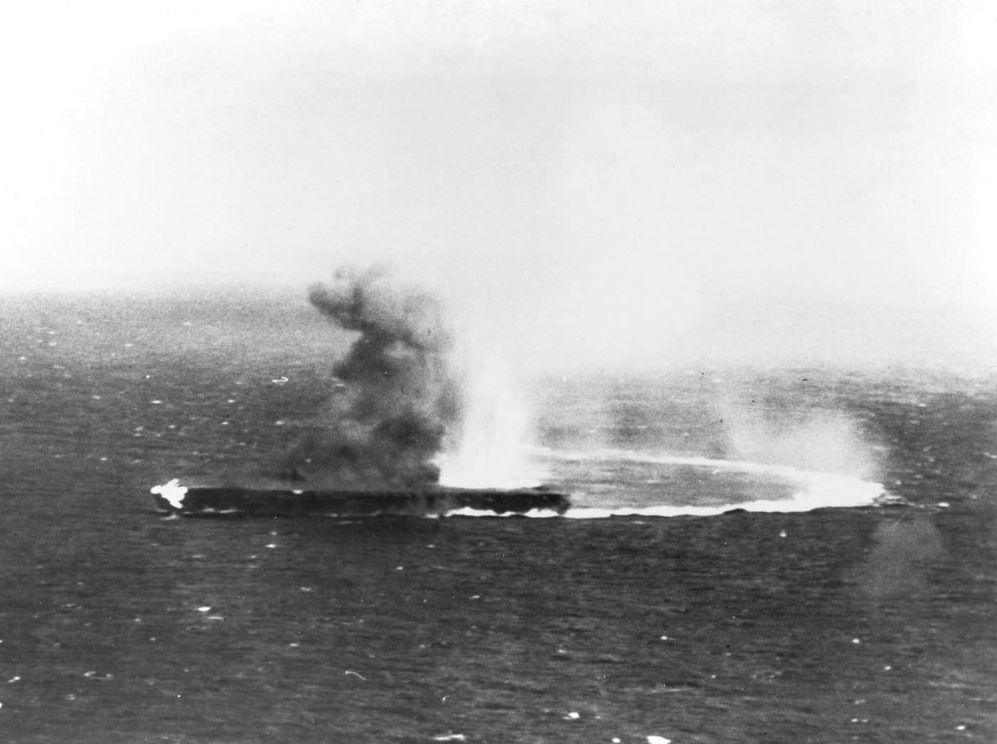 Photograph of the Japanese carrier Shokaku at sea with smoke and fire at the bow