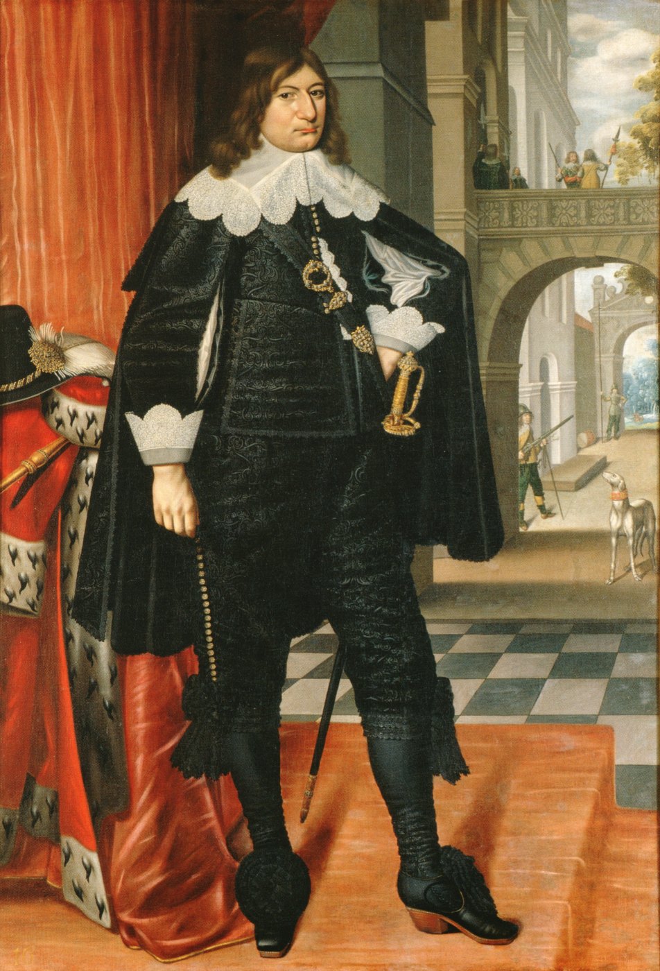 Full-length painted portrait of a young man with long brown hair, a wide lace collar and a black embroidered suit and cloak, standing in a palace hall beside a red curtain and an ermine robe, with soldiers on a balcony behind