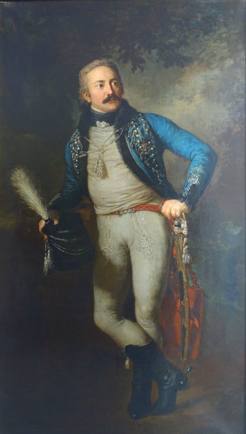 Full-length painted portrait of a young officer with a moustache in a blue hussar jacket trimmed with fur and silver braid and white breeches, holding a plumed hat and resting his hand on a curved saber