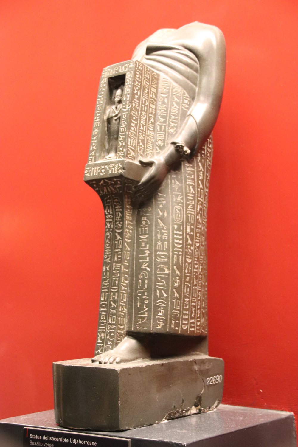 Dark stone statue of a standing Egyptian official covered in hieroglyphs