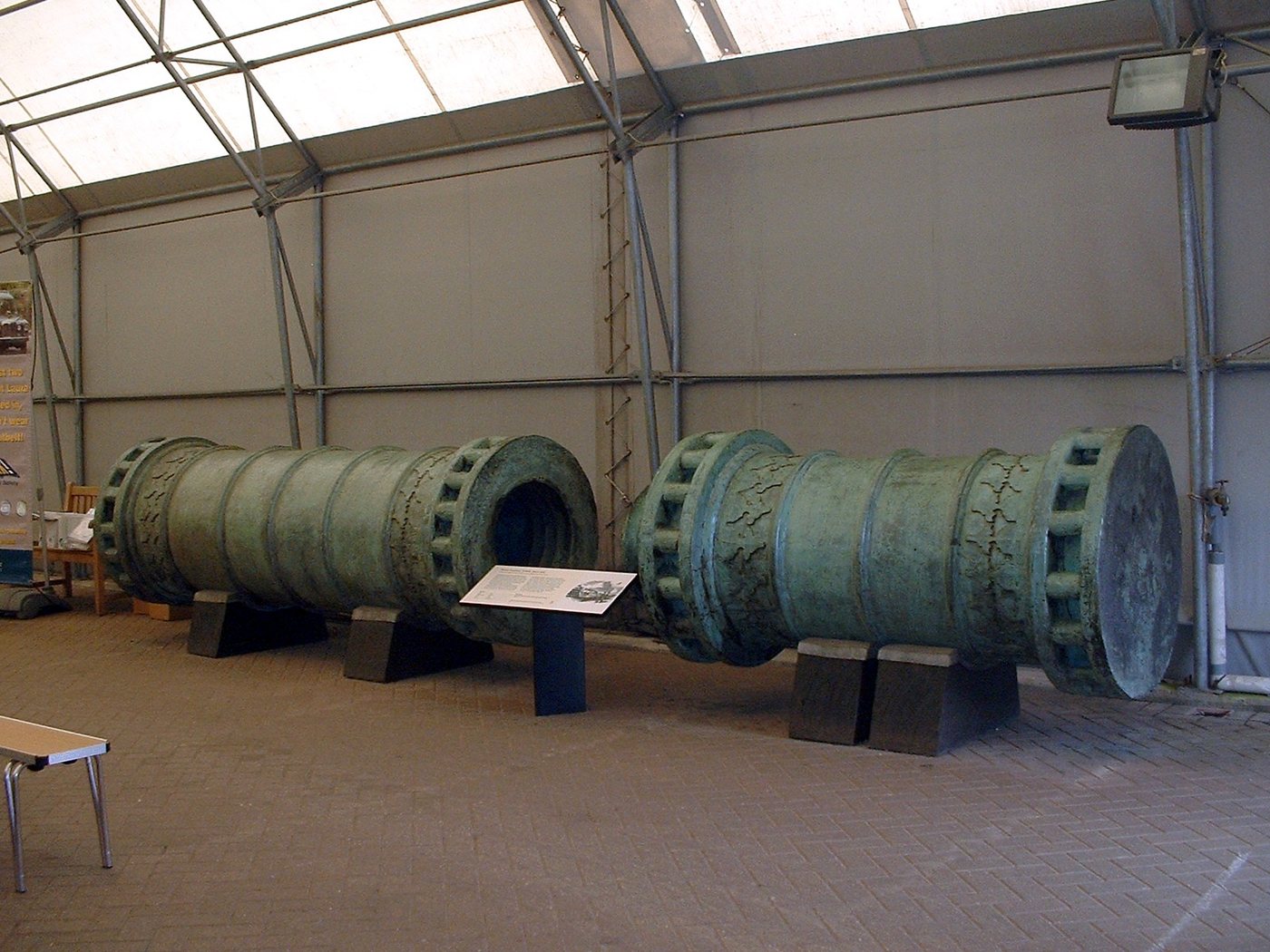 Huge green bronze cannon in two sections displayed in a museum hall