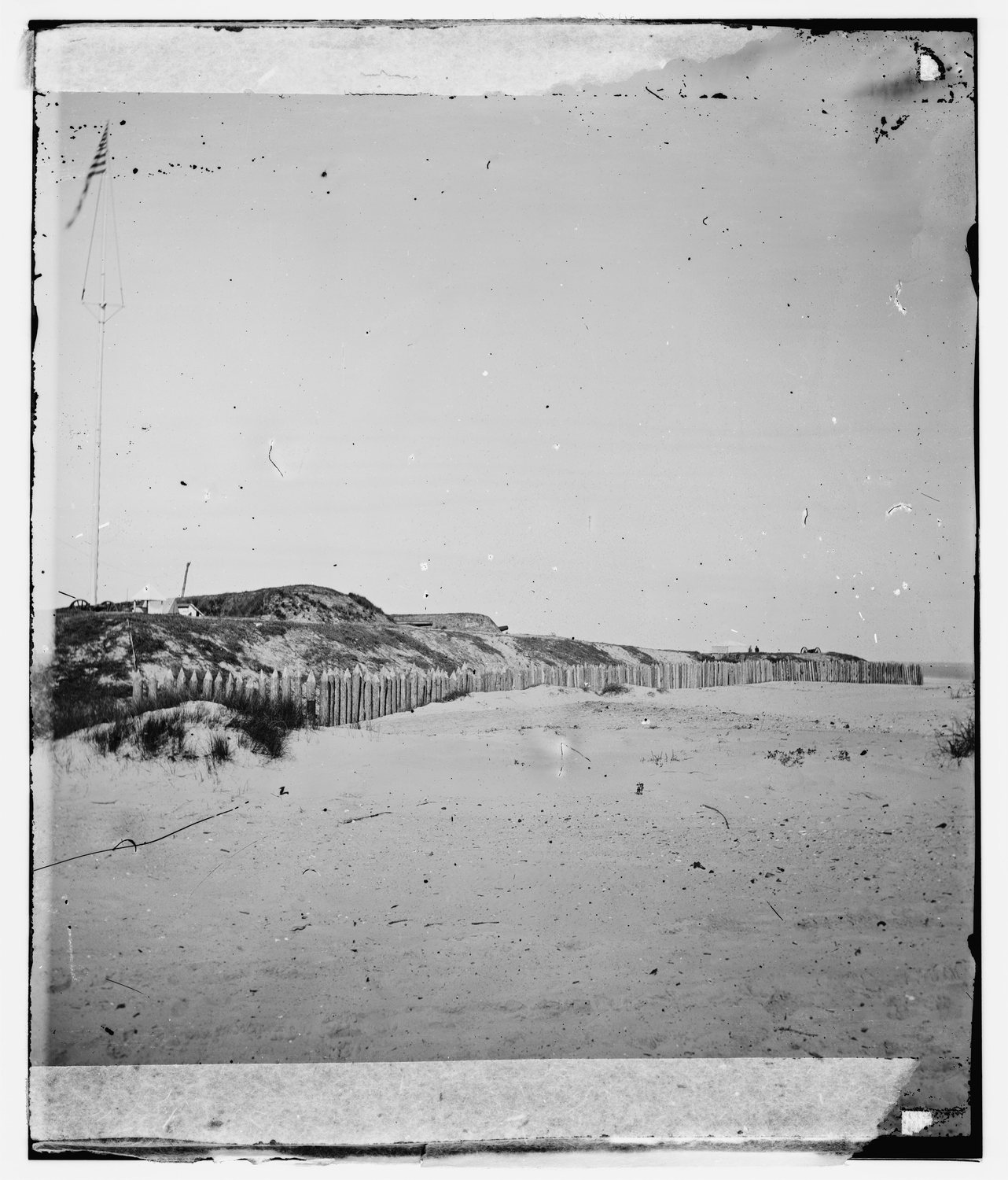 Old glass plate photograph of sand dunes and a low earthwork on a flat beach