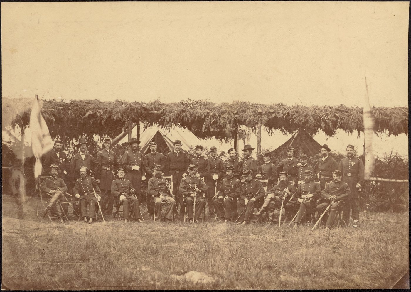 Group photograph of General Meade and his staff officers seated outdoors under a brush shelter