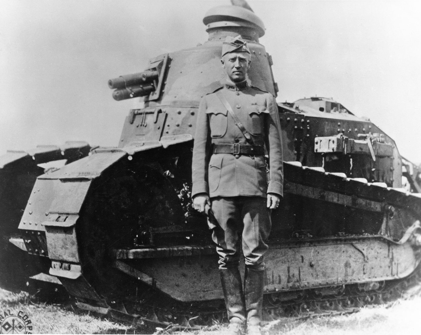 Patton in First World War uniform standing in front of a small Renault tank