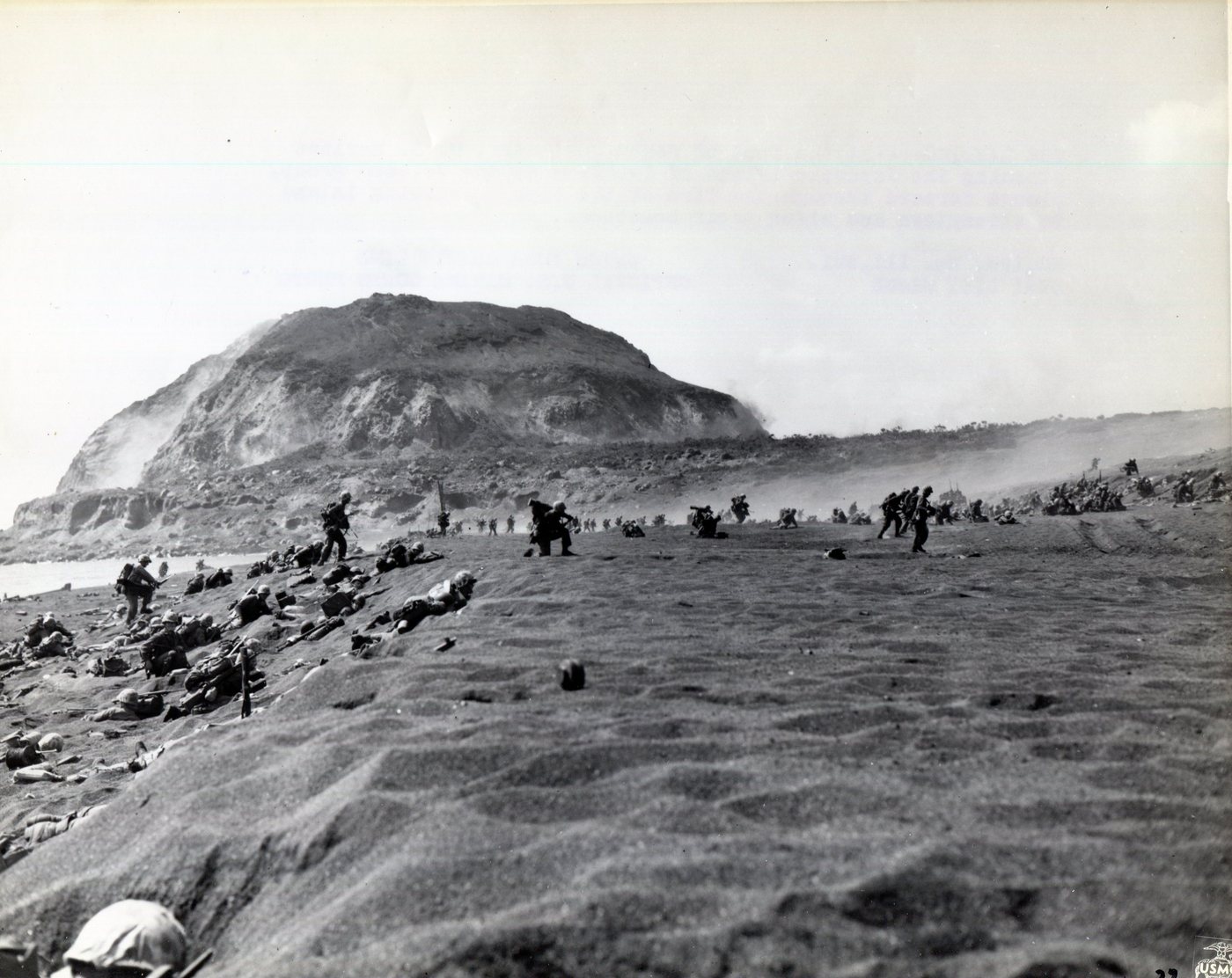 Marines spread across black volcanic sand with Mount Suribachi rising behind