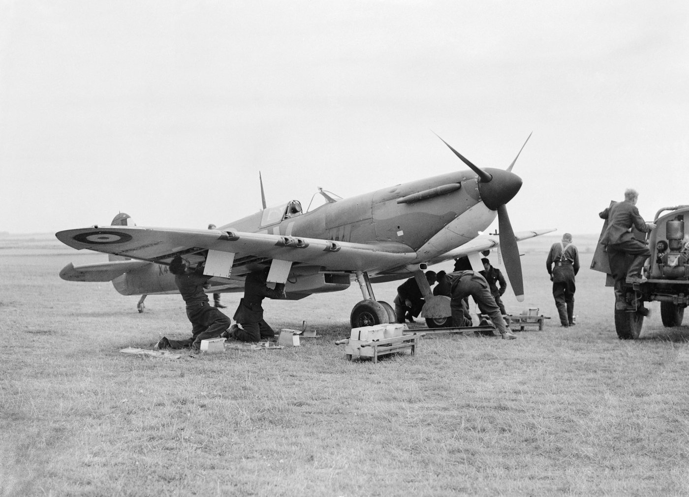 Ground crew working on a Spitfire fighter parked on a grass airfield