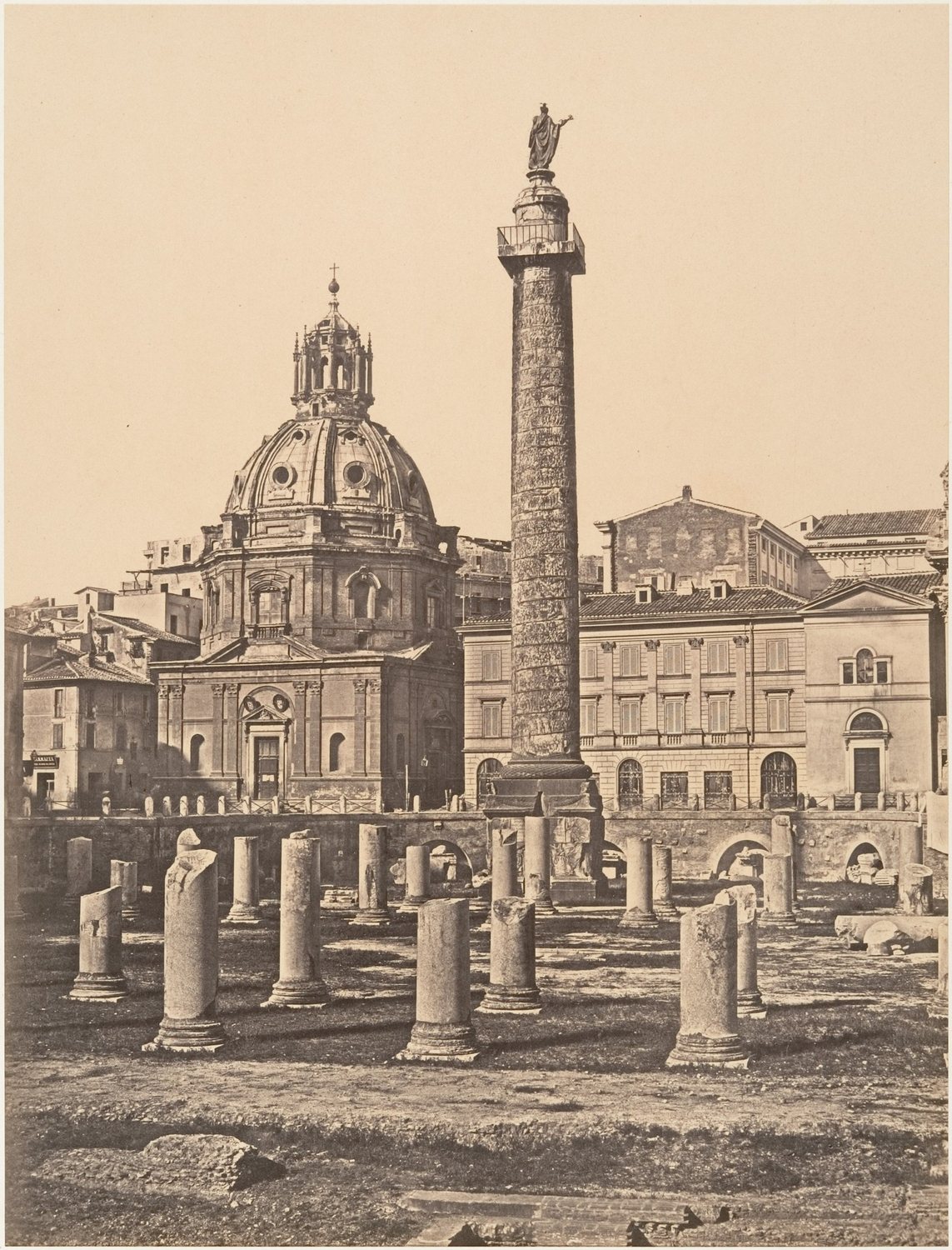 Old photograph of Trajan's Column rising above the ruined columns of the forum