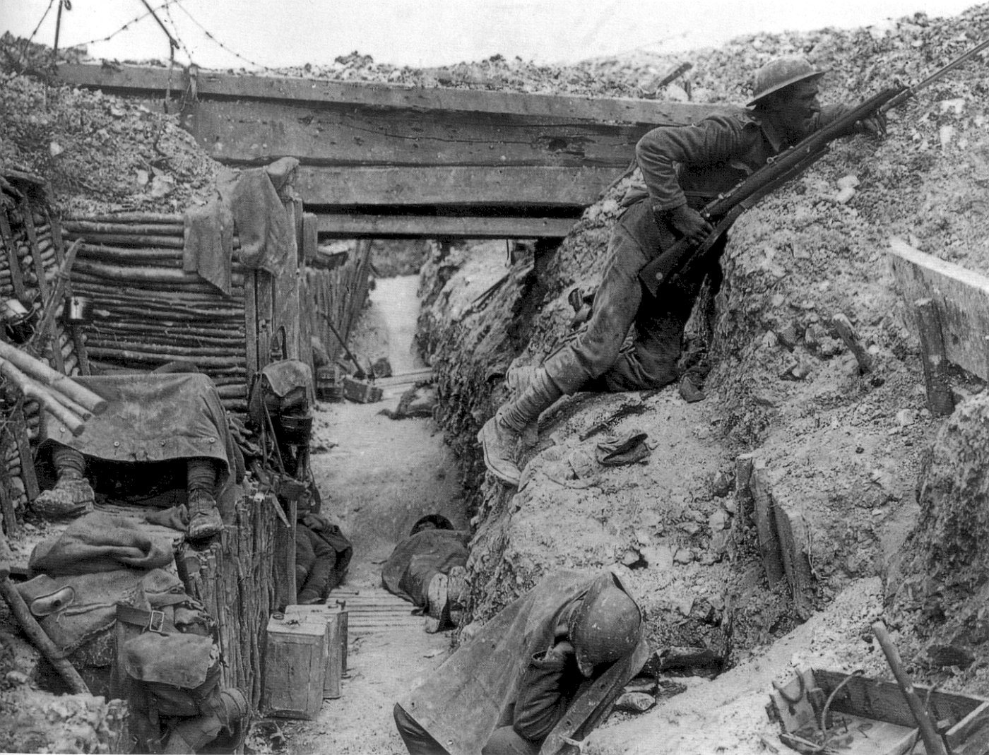 British soldiers resting in a trench while one keeps watch over the parapet