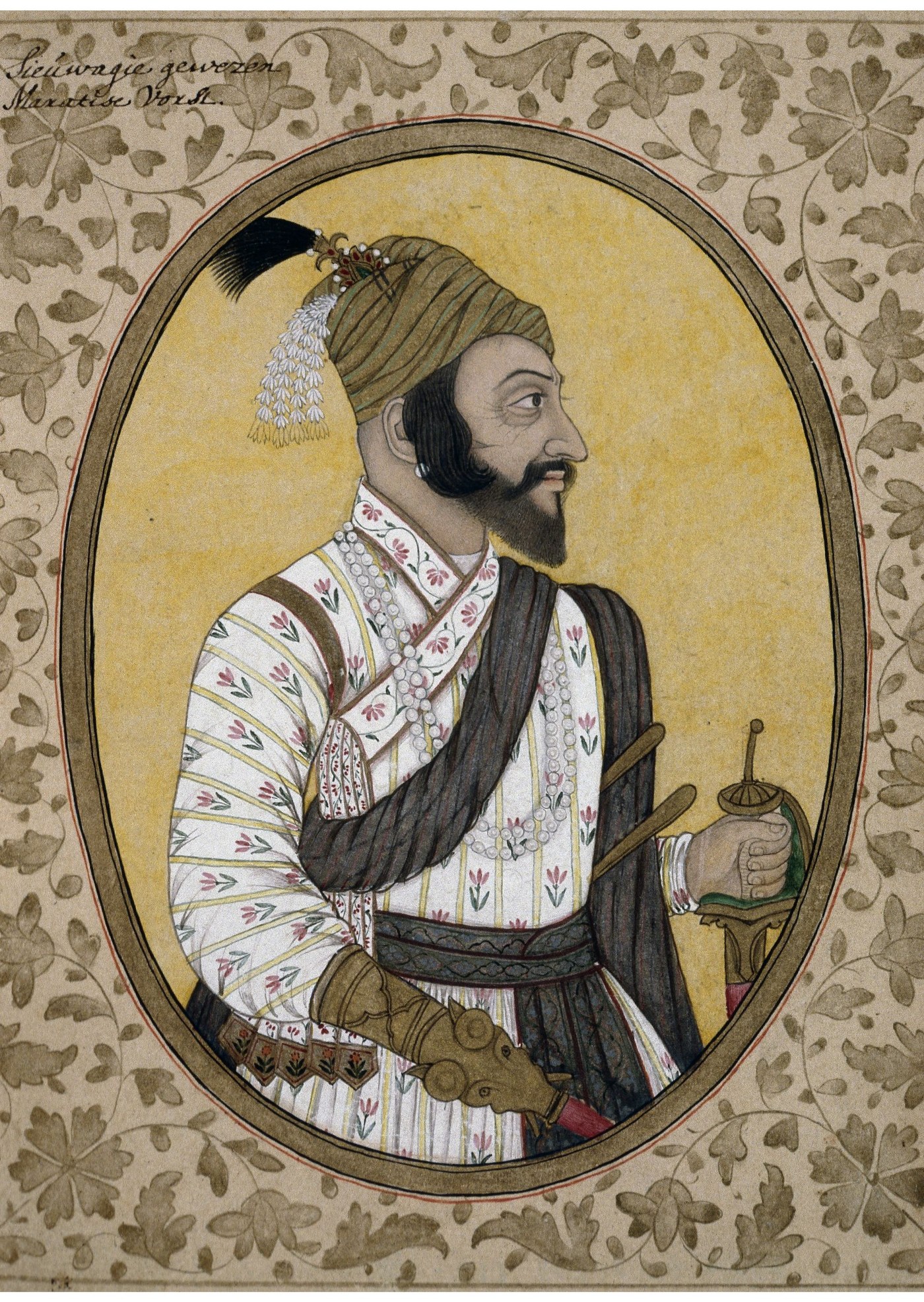 Miniature portrait in an oval frame of a bearded man in profile, wearing a striped turban with a plume and pearls, a long white robe with small red flowers, a dark sash and a patterned belt, holding a sword hilt, against a yellow background inside a border of gray foliage.