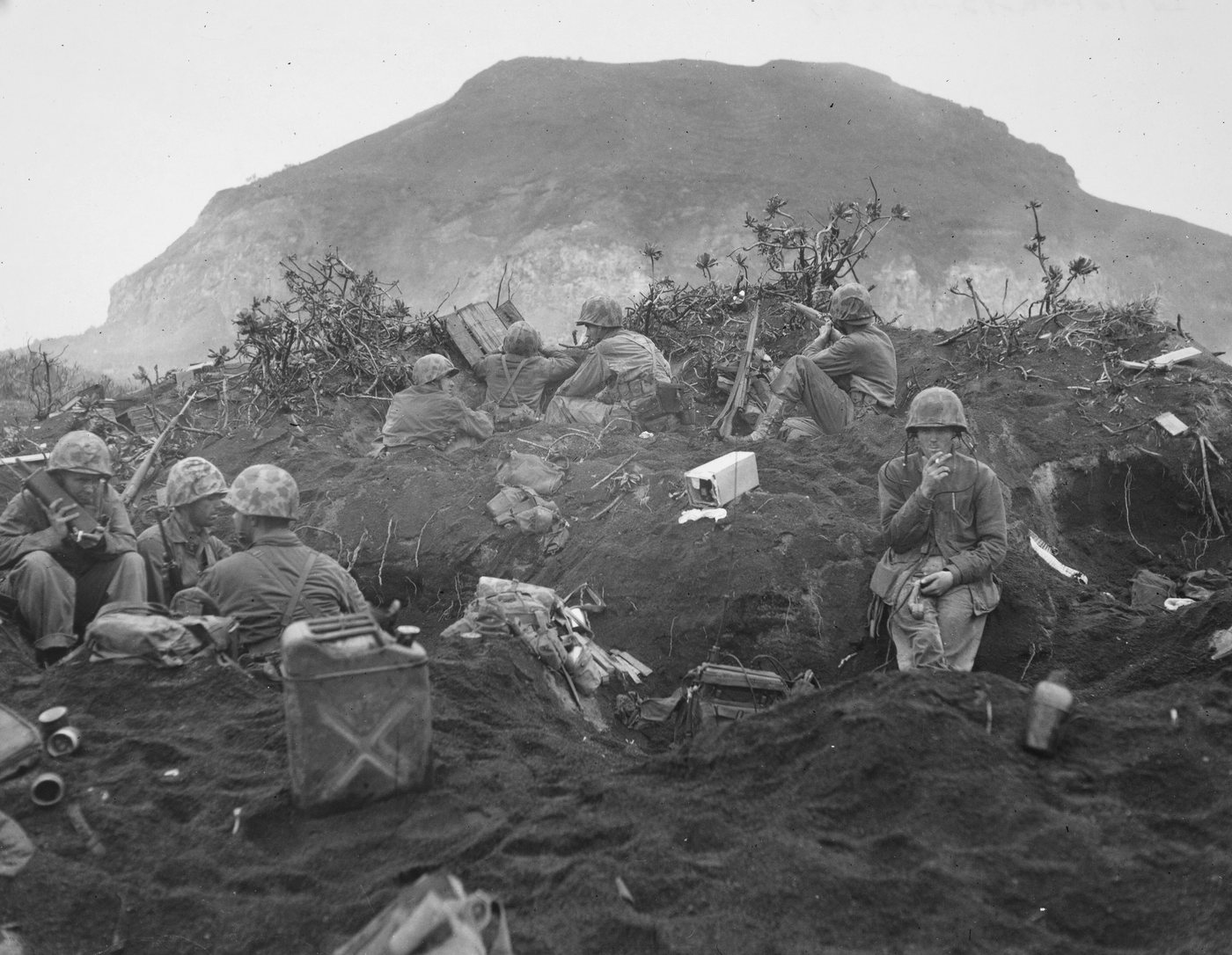 Marines dug into volcanic sand below the bulk of Mount Suribachi