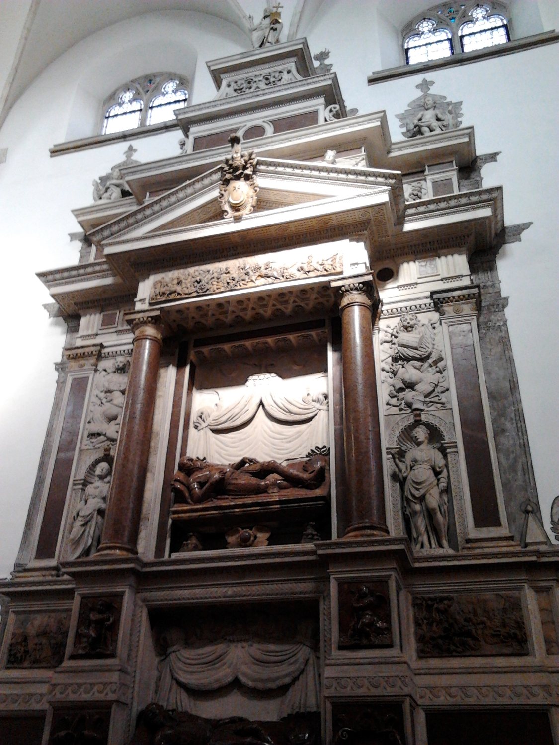 Tall marble and stone Renaissance tomb with recumbent effigies set into a church wall