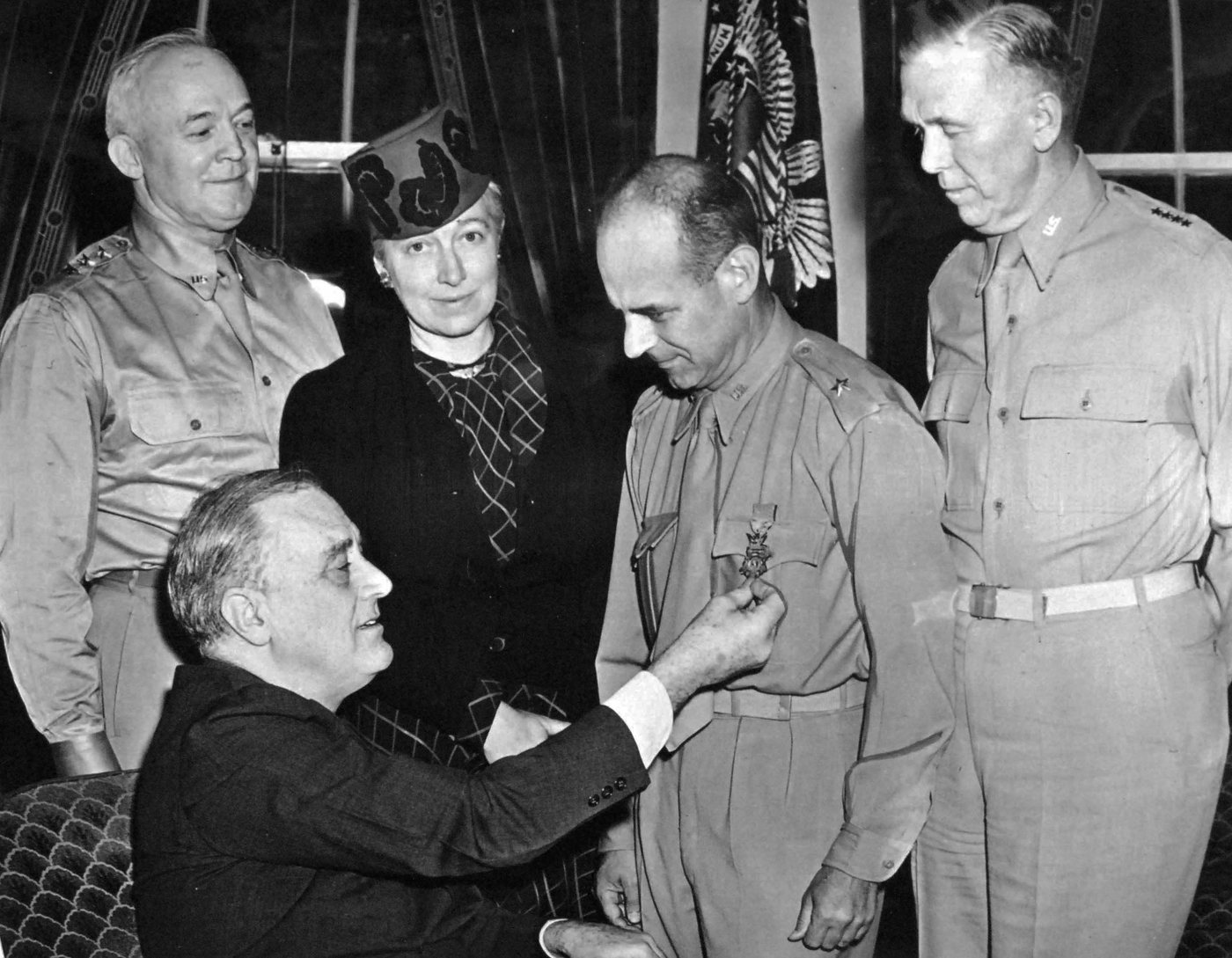 Black and white photograph of President Roosevelt at his desk pinning a medal on Doolittle
