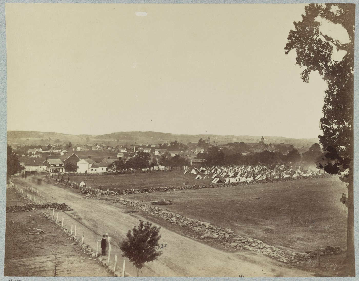 Black and white photograph of a small town and fields seen from a hilltop