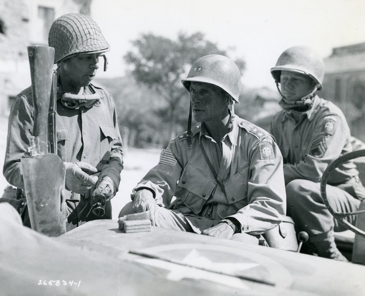 Three American soldiers in helmets talking in a jeep, 1943