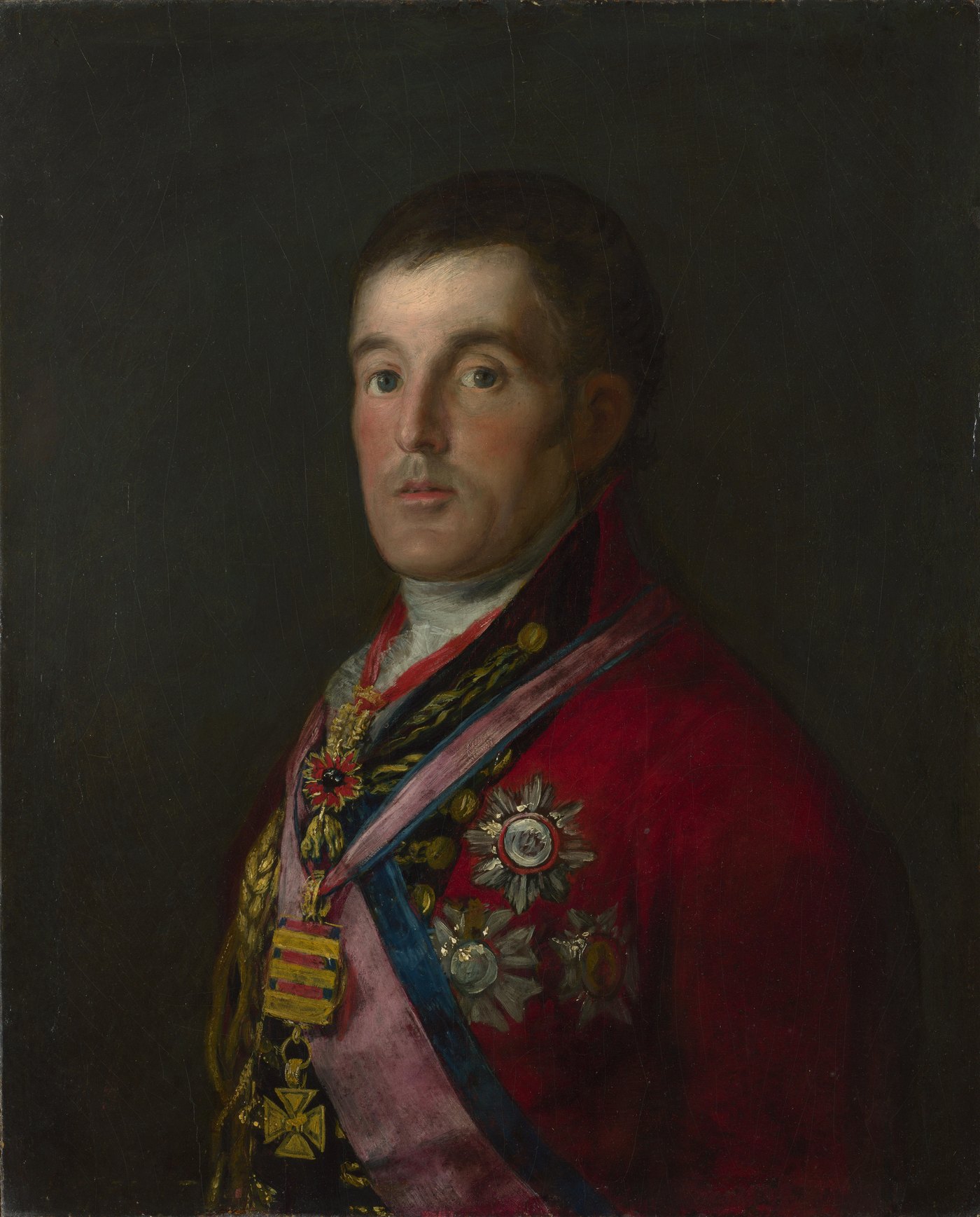 Half-length oil portrait of a man with dark curly hair in a red general's coat covered in gold braid, orders and a medal cross, against a dark background.