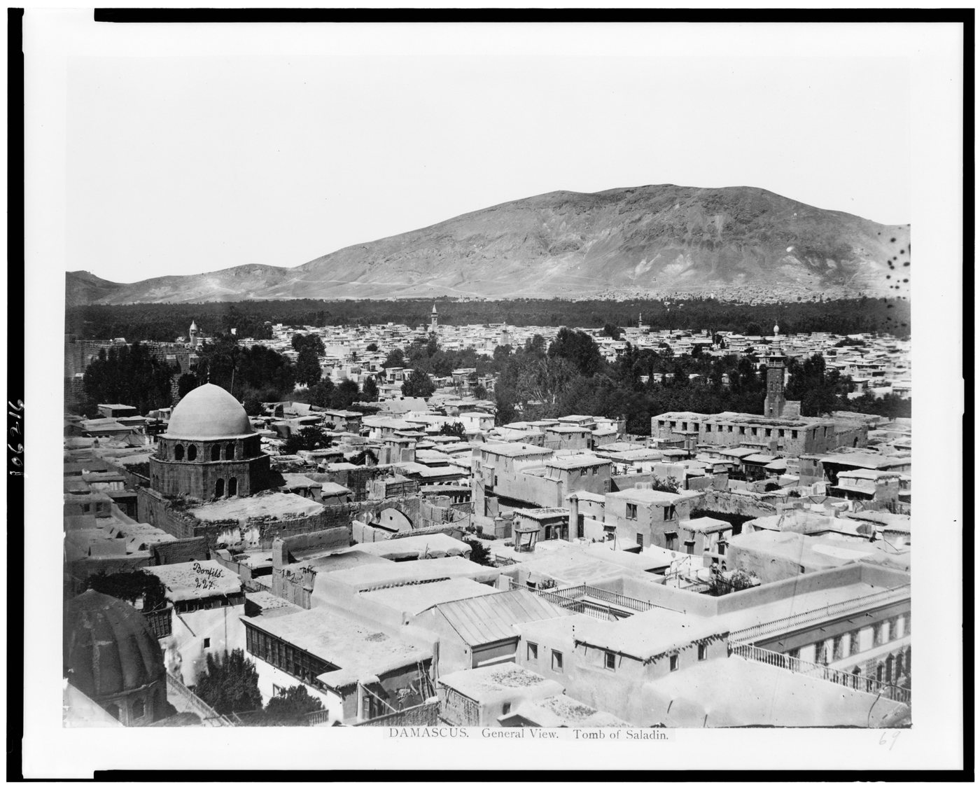 Old photograph of the rooftops and domes of Damascus with a mountain behind