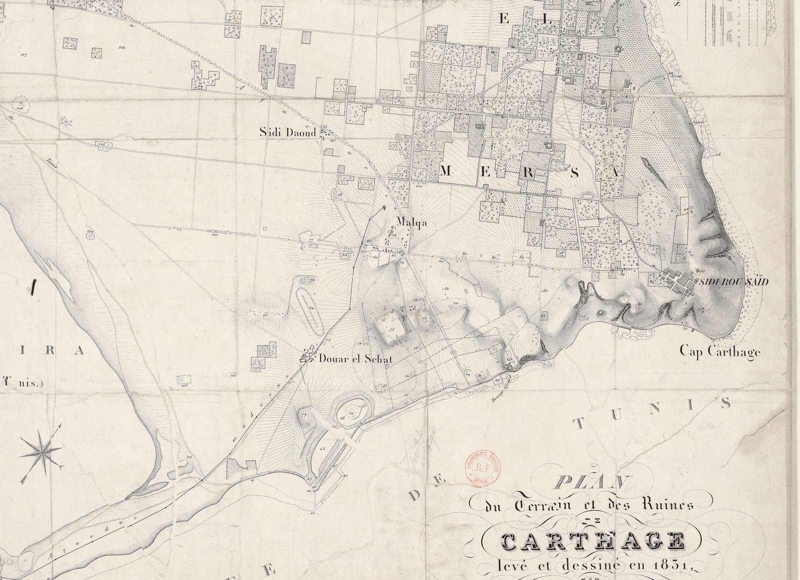 Black and white survey map of a coastal plain: a lagoon at left, a long sandbar running down to a fort at the bottom left, two small artificial basins near the shore, one round with an island in the middle, low hills and villages inland, a cape and a village on a cliff at right, and an ornate title cartouche reading Plan du terrain et des ruines de Carthage