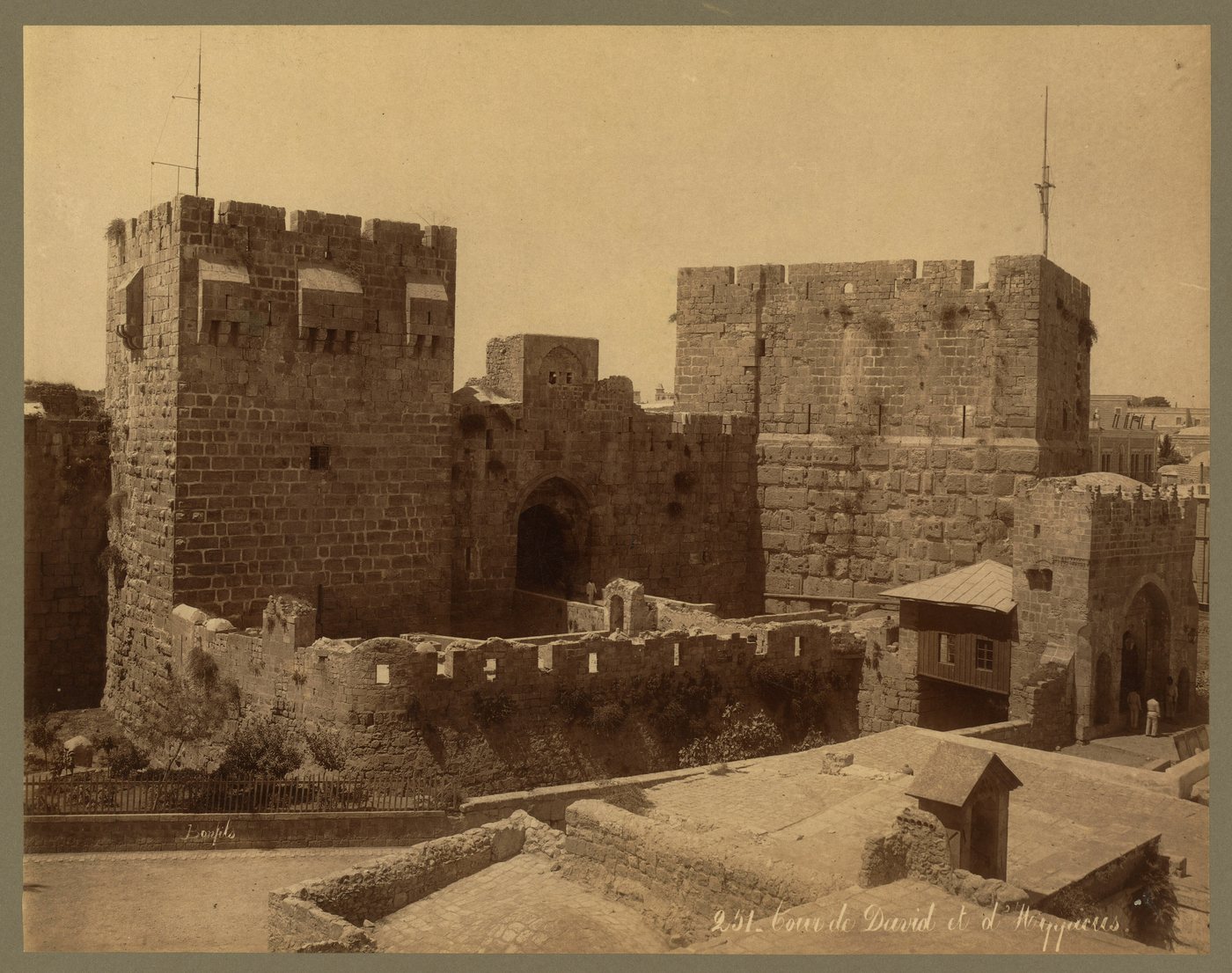 Old sepia photograph of massive stone towers of a citadel above a moat