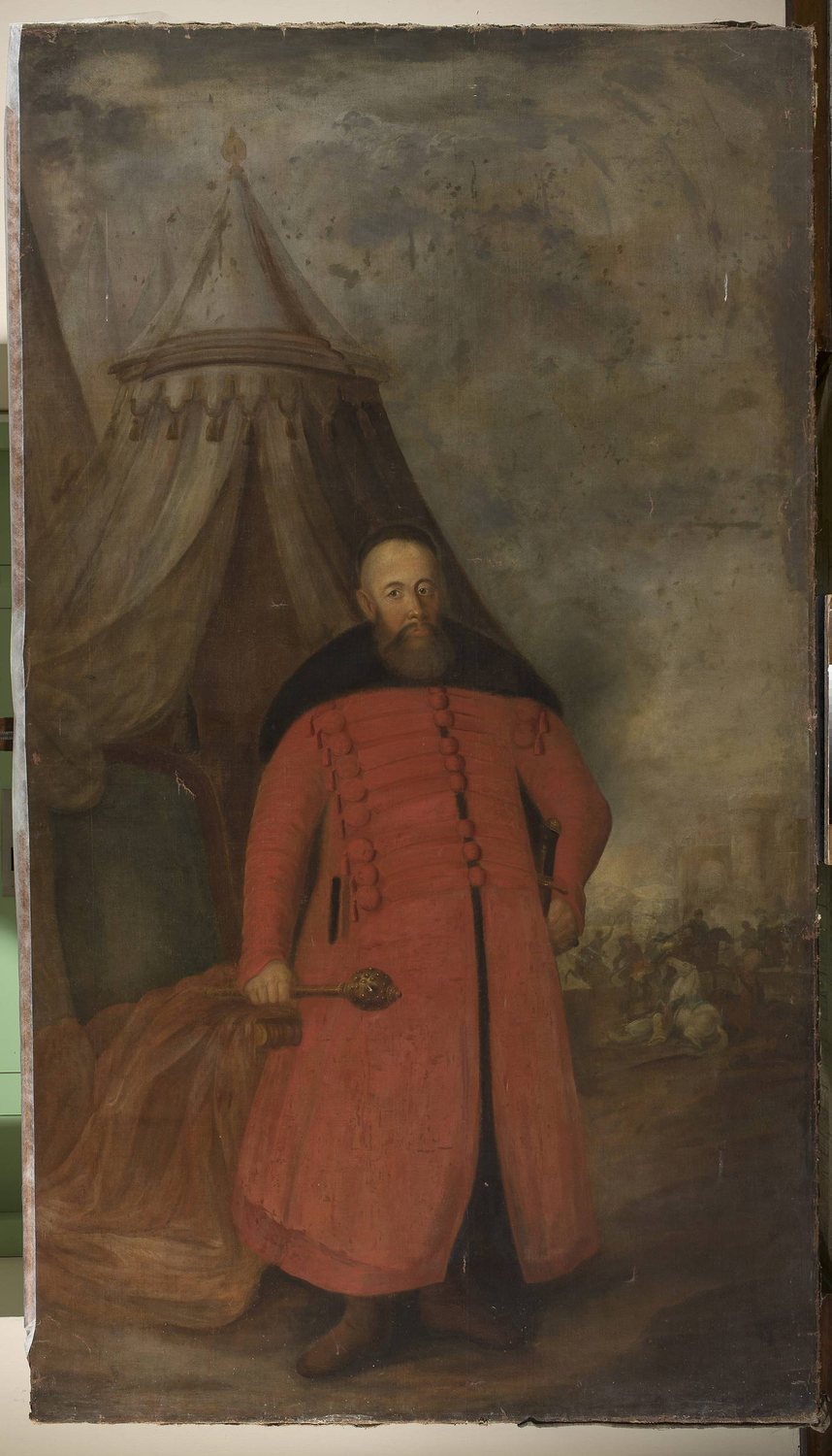 Full-length portrait of Koniecpolski in a long red robe holding a mace, a tent behind him