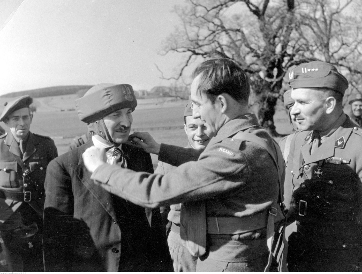 A paratrooper places a padded training helmet on Clement Attlee while Sosabowski watches on the right