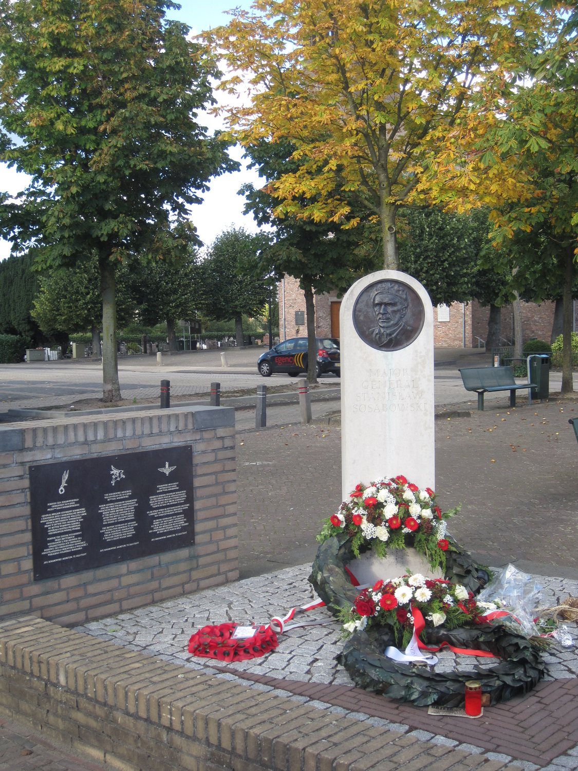 White stone monument with a bronze portrait relief of Sosabowski, wreaths laid at its foot