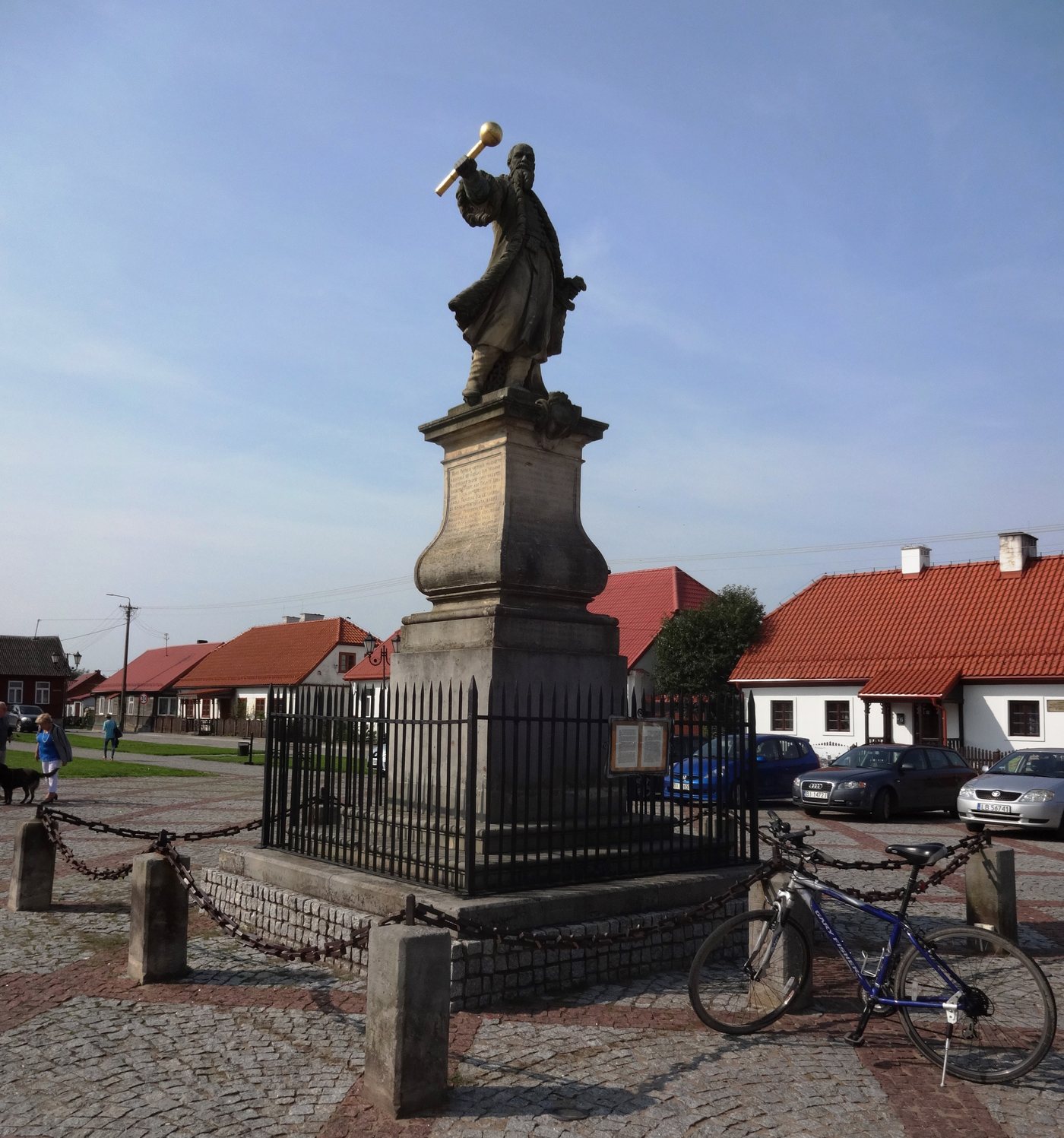 Kamienny posąg Czarnieckiego wznoszącego buławę na wysokim cokole na rynku małego miasteczka