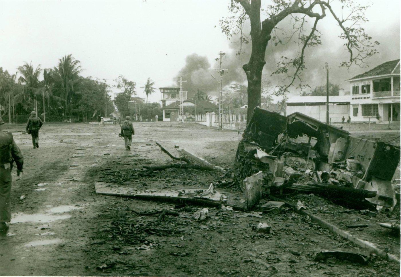 Marines advancing along a damaged street in Hue past wrecked vehicles and smoke