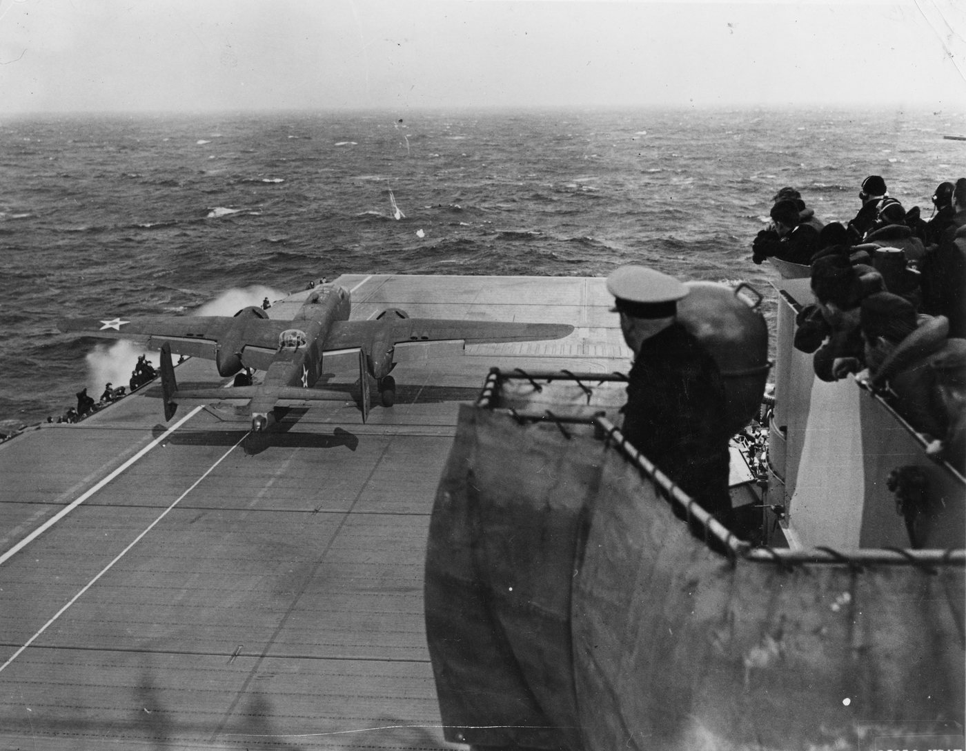 Dwusilnikowy bombowiec B-25 odrywa się od pokładu lotniskowca USS Hornet, a marynarze patrzą