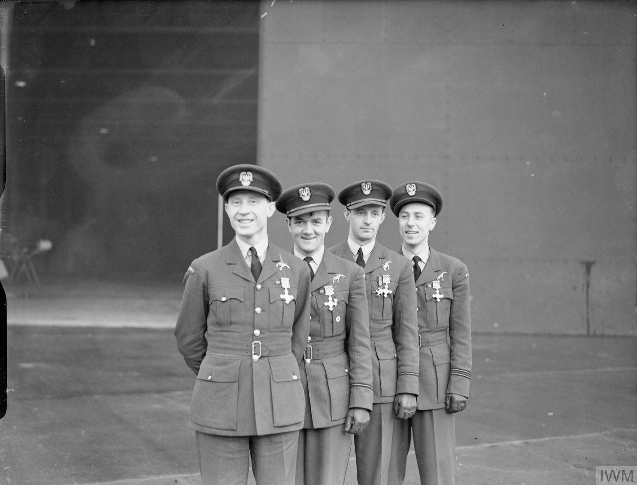 Four Polish RAF officers in caps and uniforms standing in a row wearing their new medals